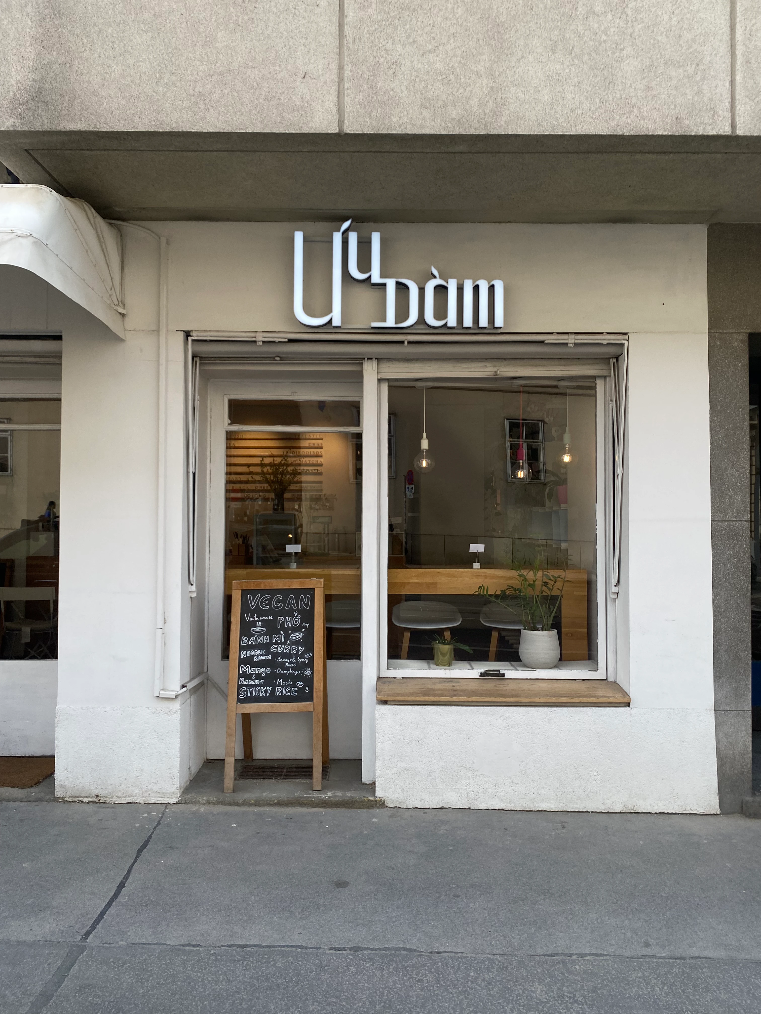 Fassade des veganen Restaurants Lú Dùm mit Speisekarte auf einer Tafel.