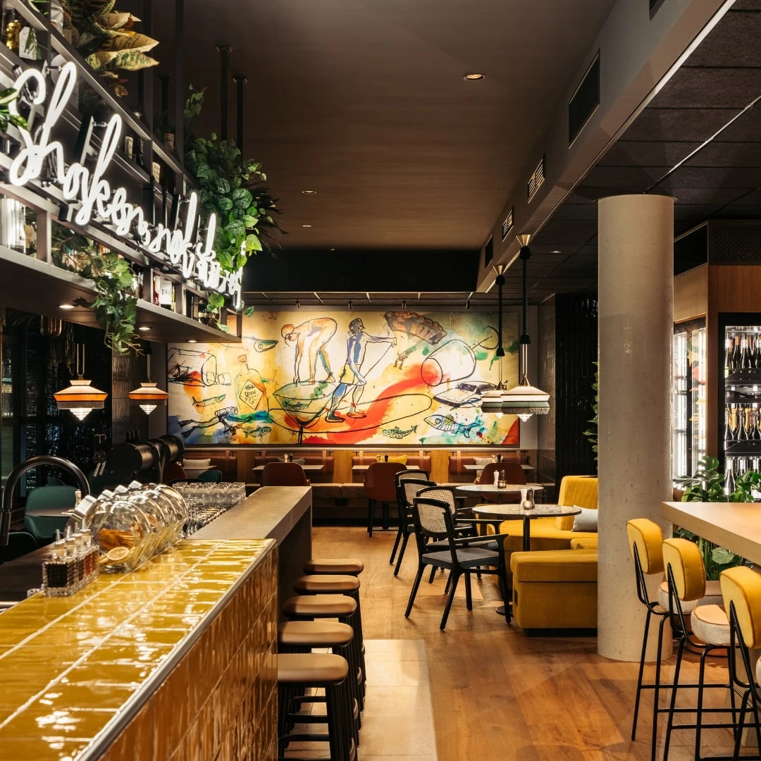 Stilvolles Restaurant mit gelben Akzenten, Bar und moderner Kunst.