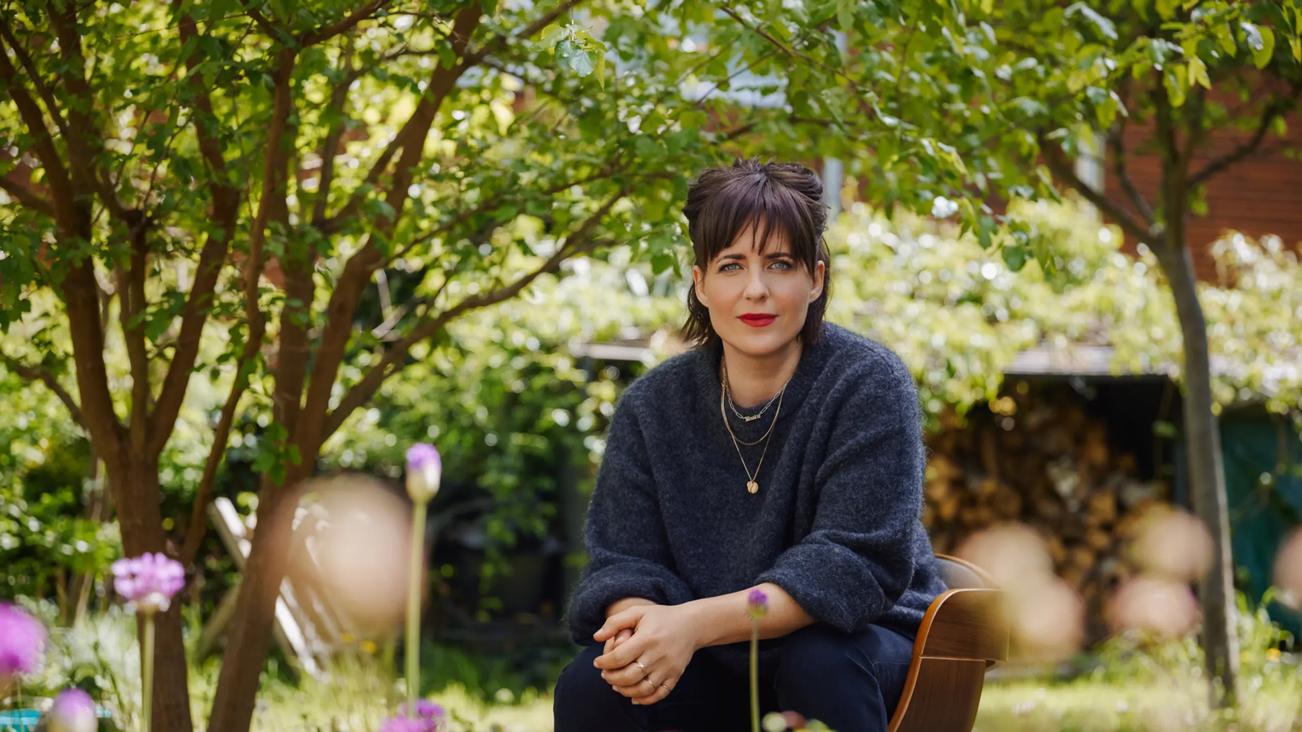 Sarah Kuttner sitzt in einem Garten