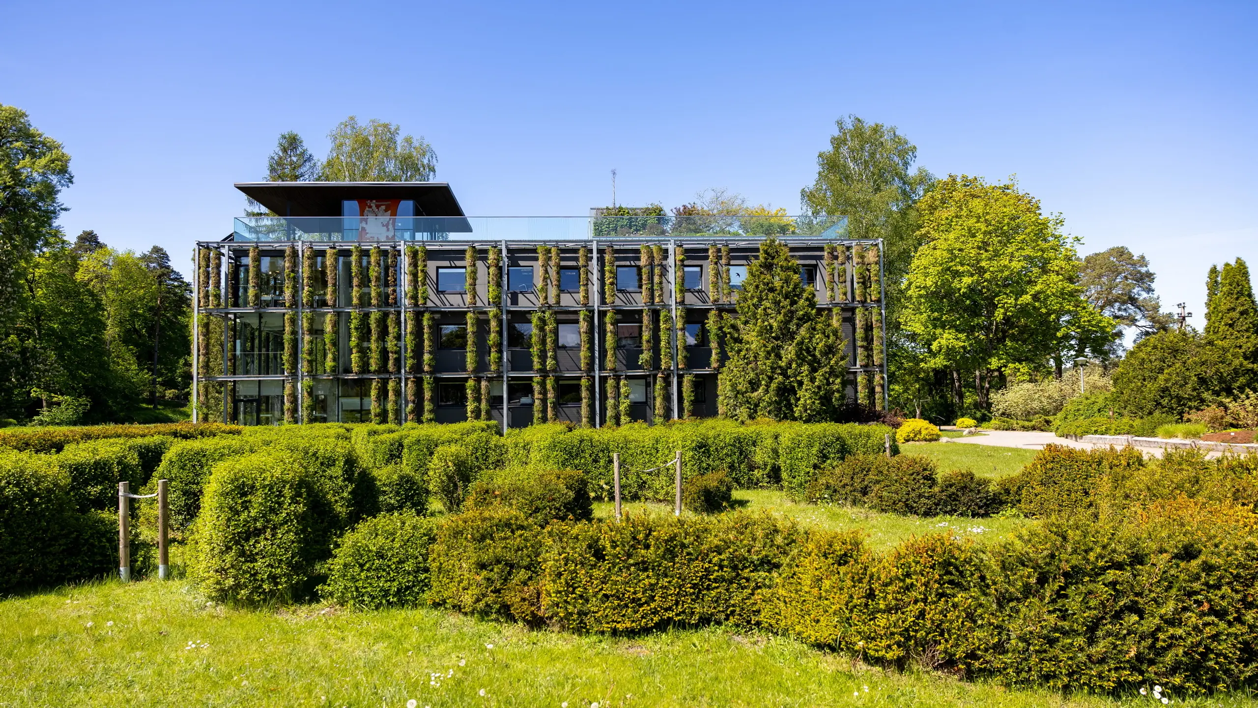 Begrünte Frontansicht des ehemaligen Laborgebäudes der Universität