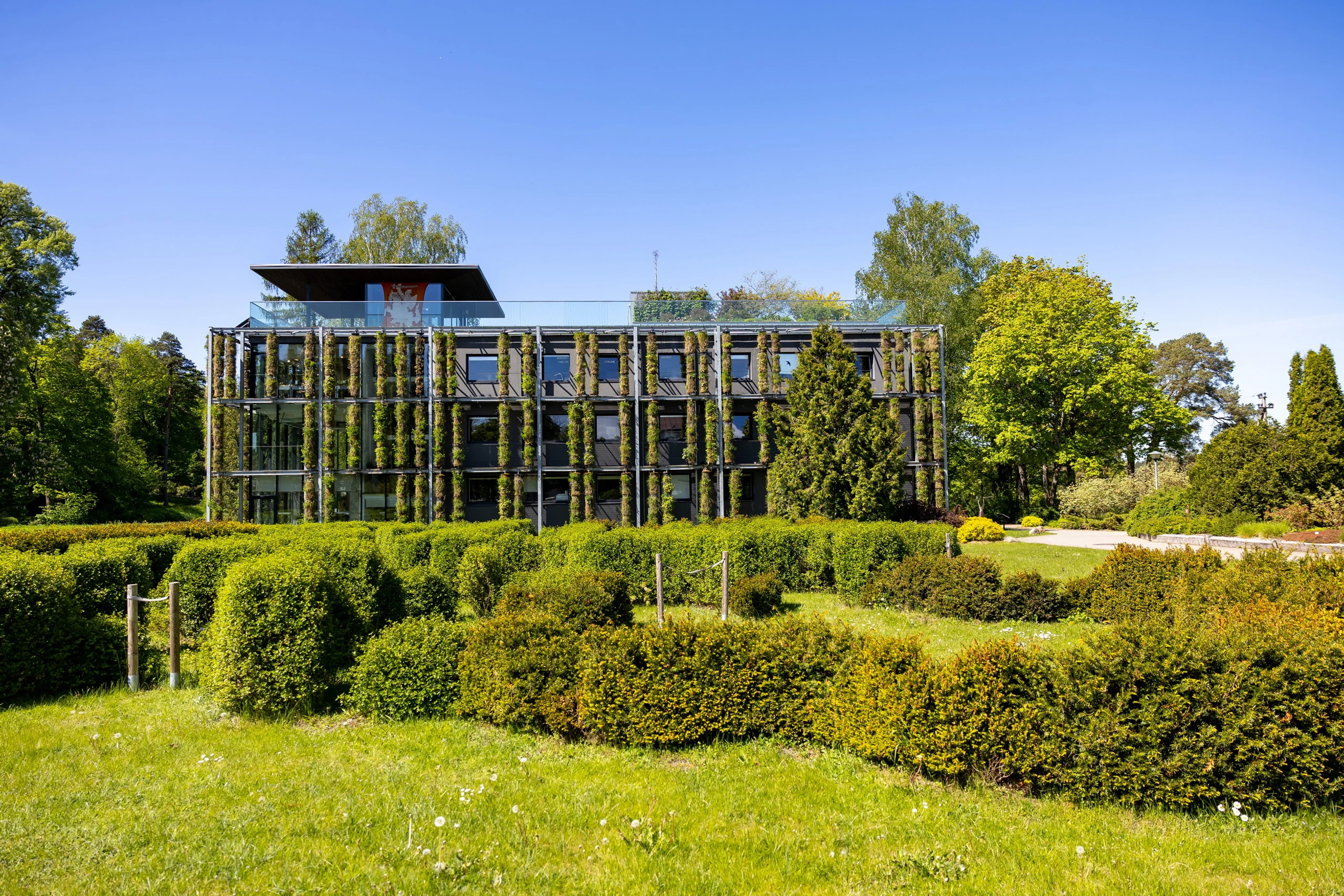 Begrünte Frontansicht des ehemaligen Laborgebäudes der Universität