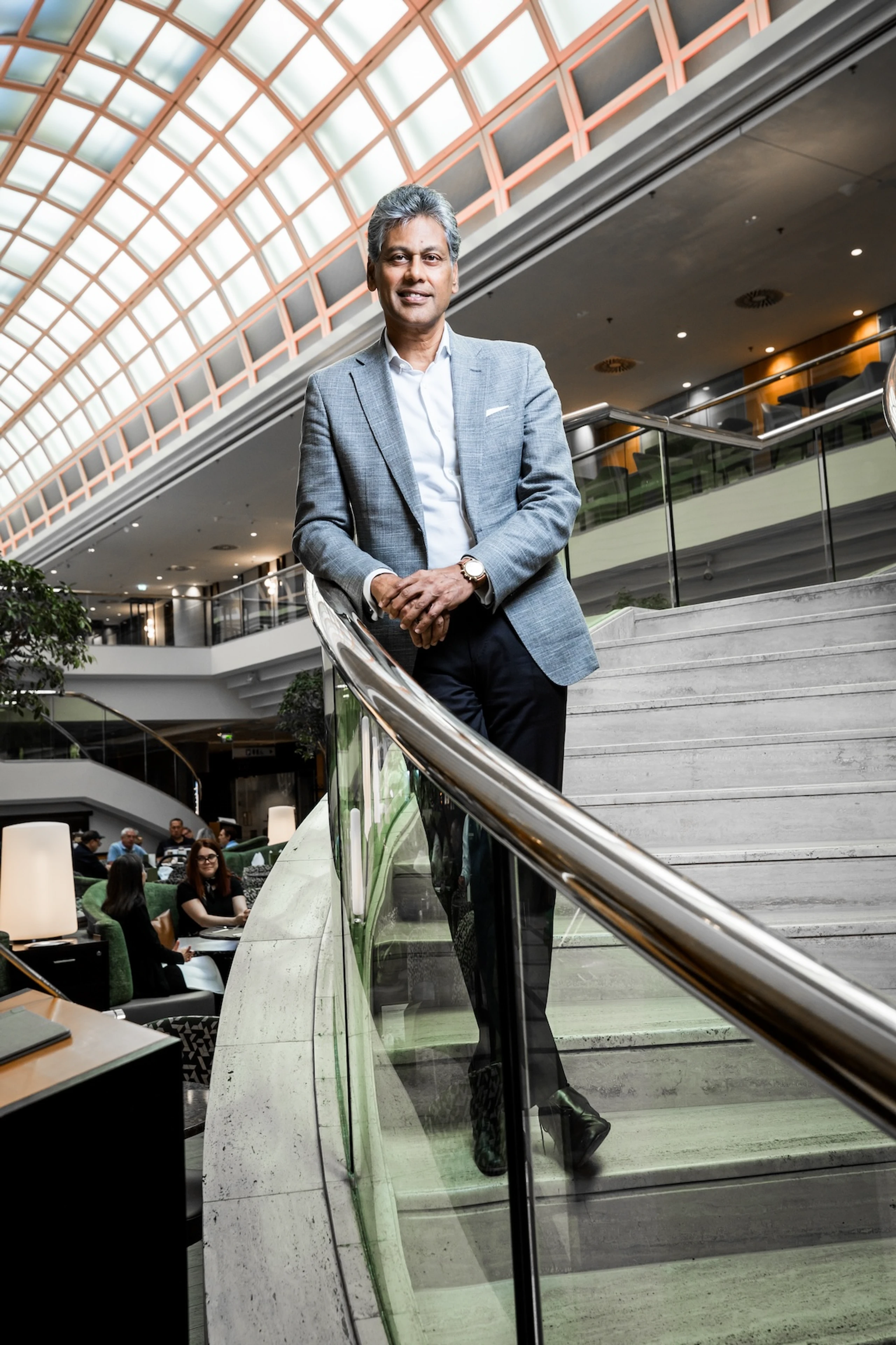 Satya Anand steht in einem grauen Anzug in einem seiner Marriott-Hotels und lächelt in die Kamera.