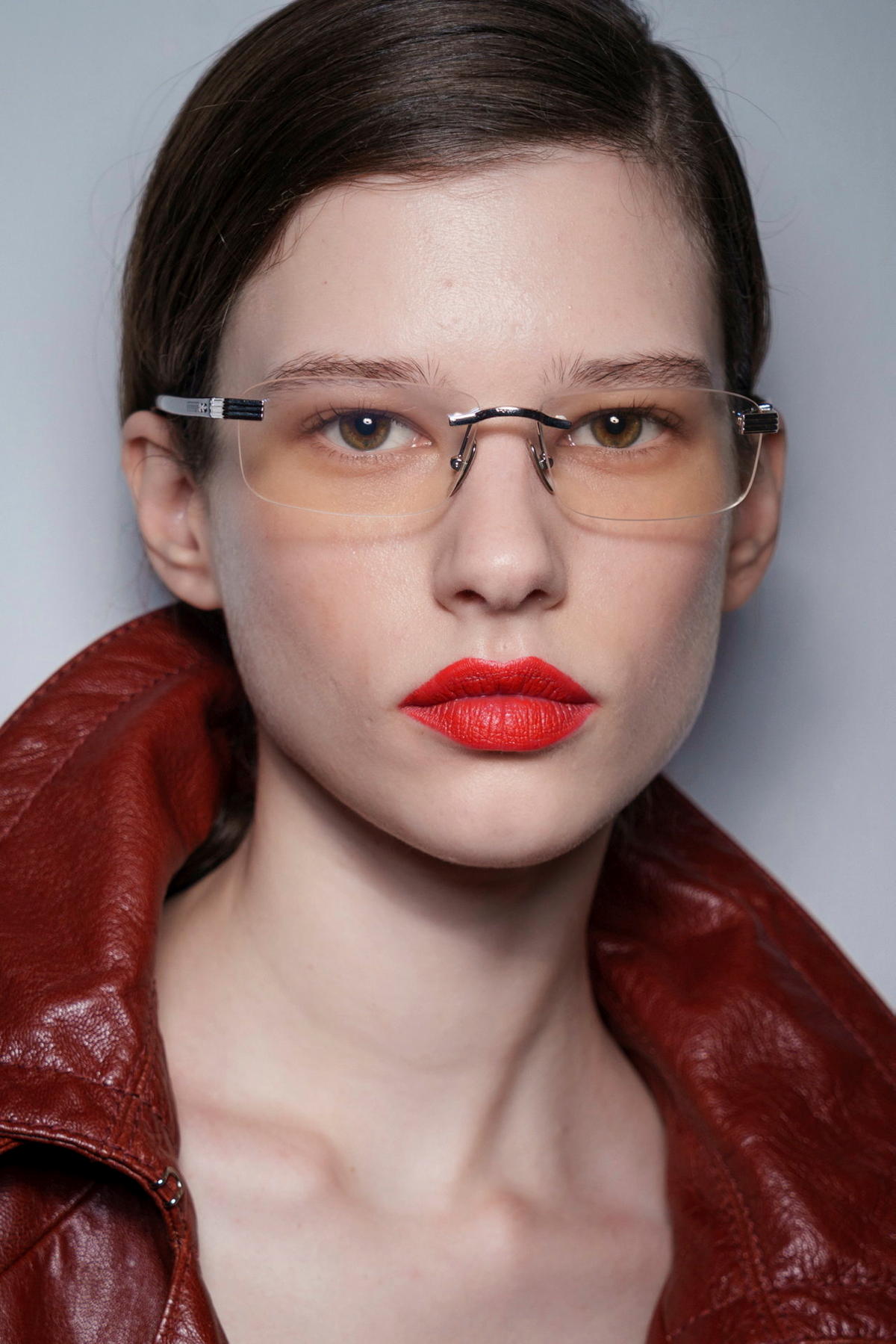 Model mit roten Lippen, transparenter Brille und zusammengebundenen Haaren
