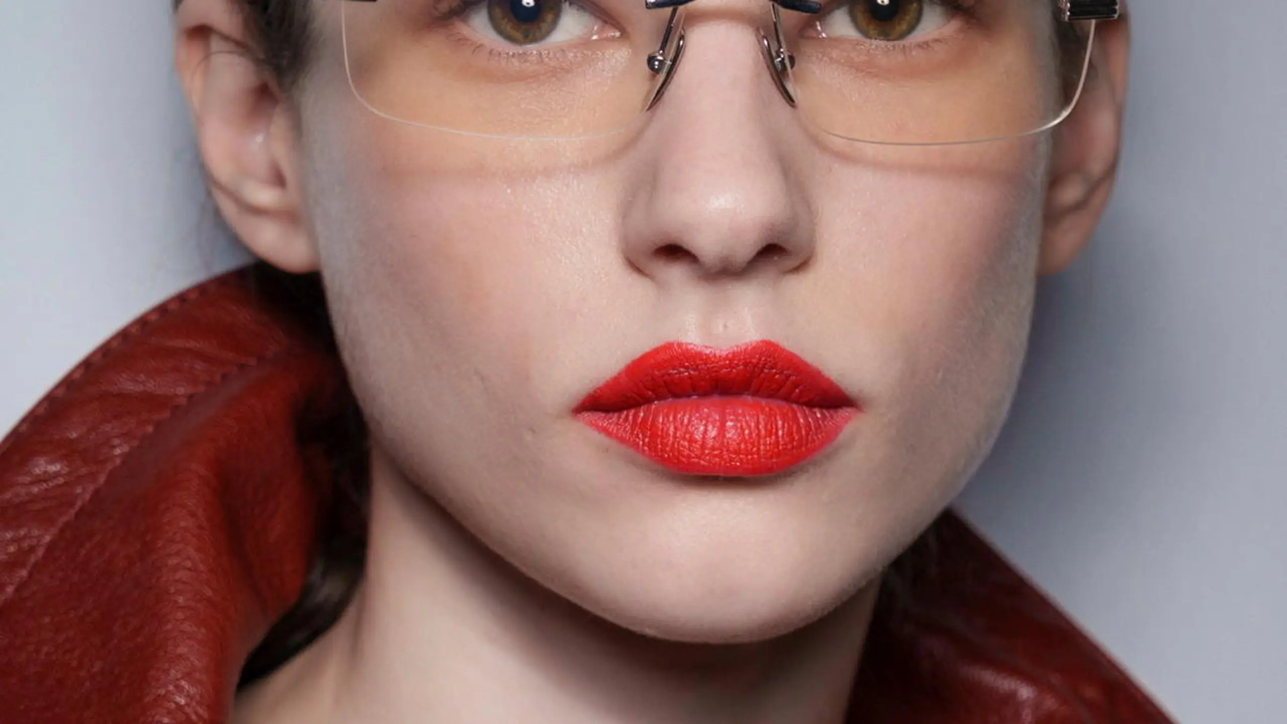 Model mit roten Lippen, transparenter Brille und zusammengebundenen Haaren