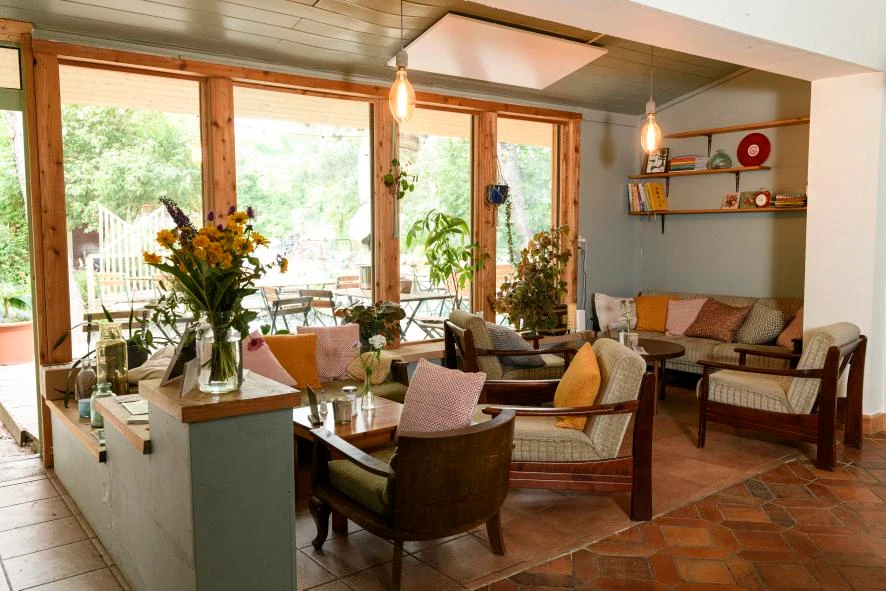 Gemütlicher Innenraum mit Sesseln, Pflanzen und Bücherregalen.