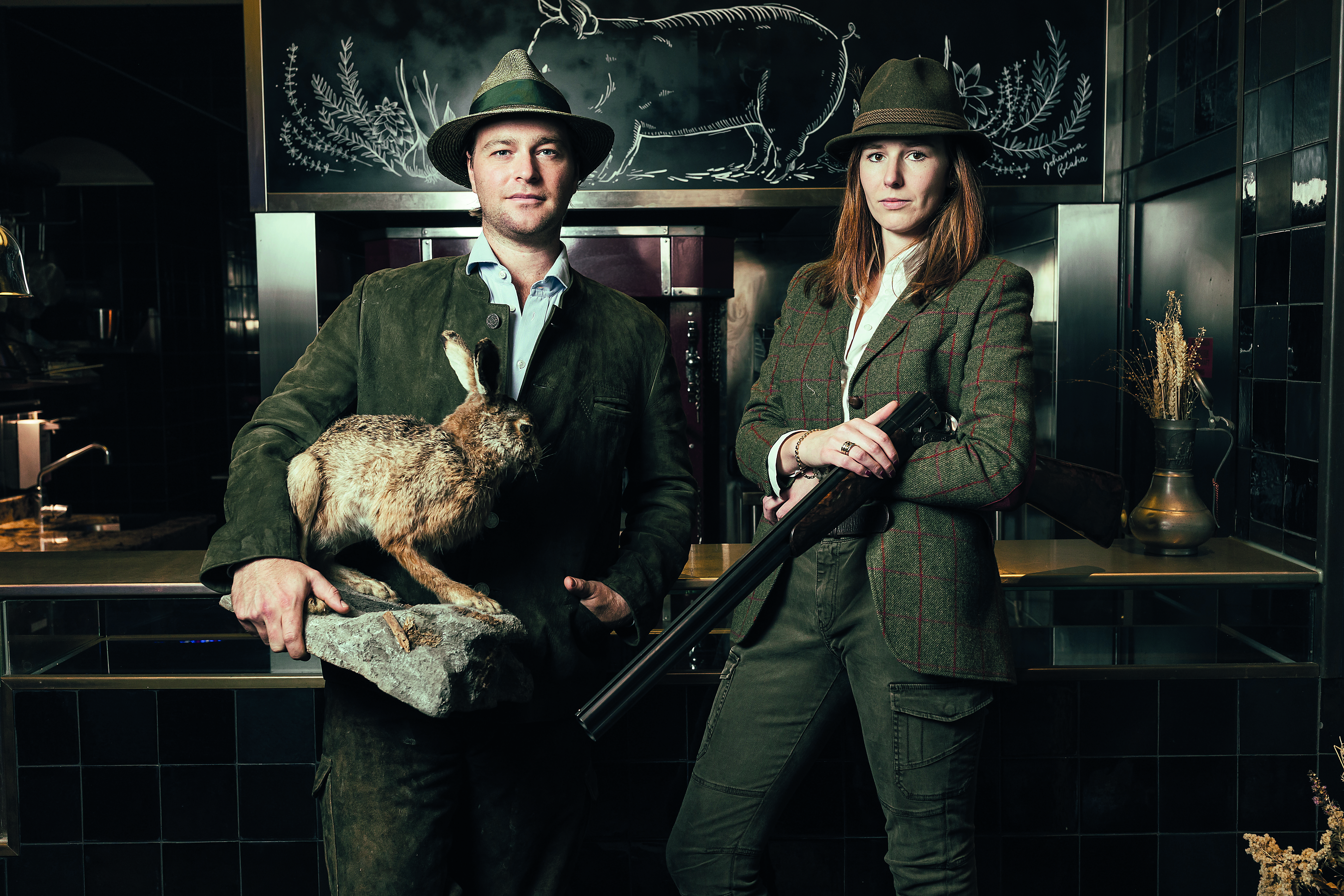 Tono Soravia und Paula Mayer-Heinisch in Jagdausrüsstung mit Gewehr, Hut und totem Hasen