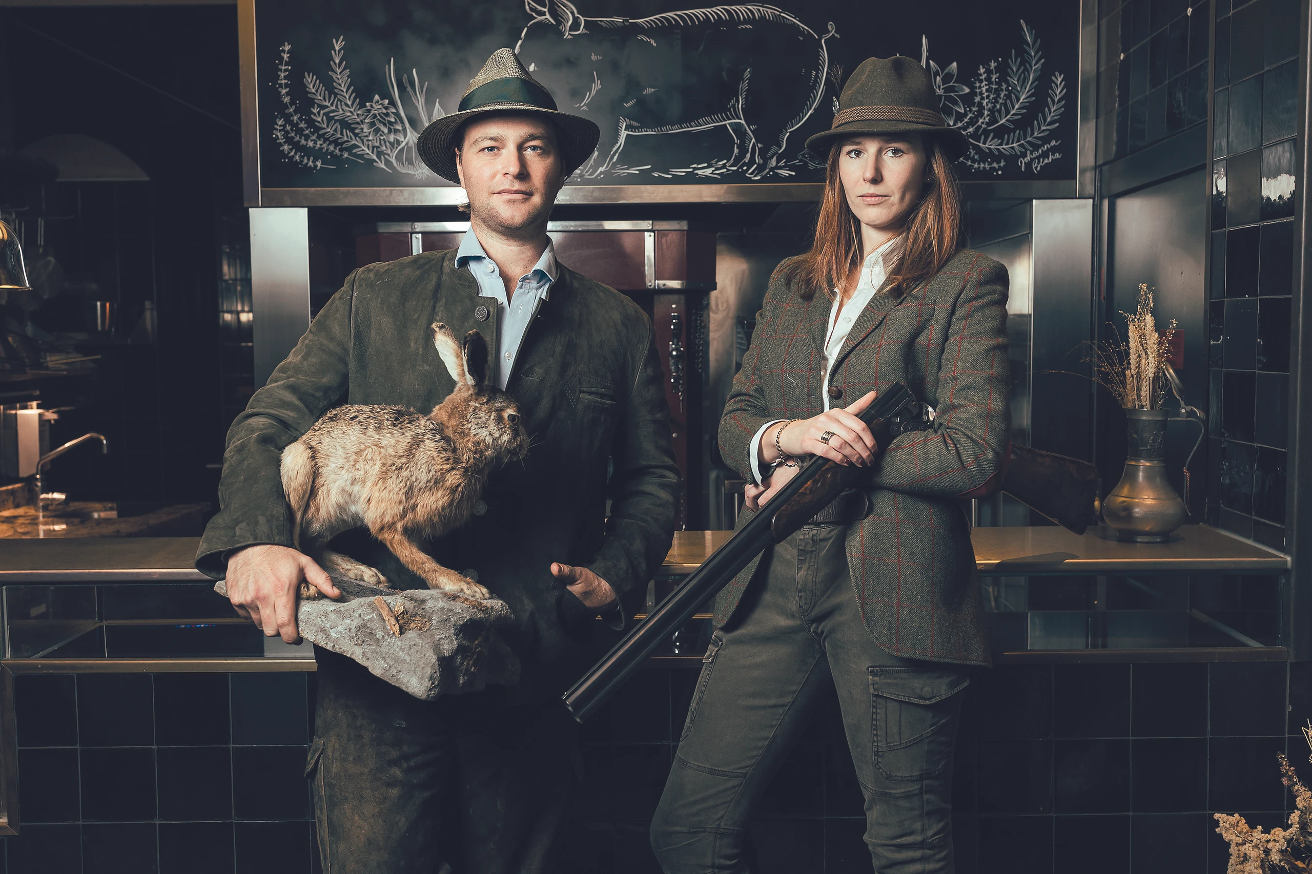 Tono Soravia und Paula Mayer-Heinisch in Jagdausrüsstung mit Gewehr, Hut und totem Hasen