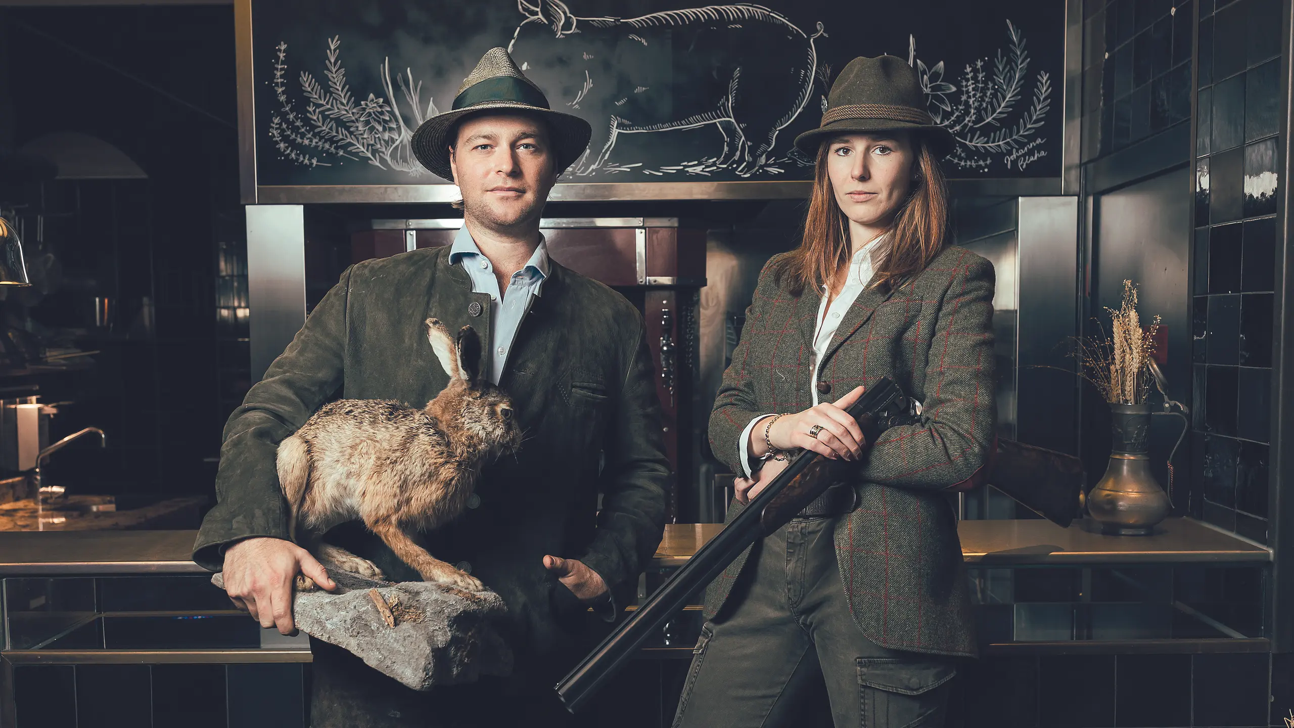 © trend/Lukas Ilgner Tono Soravia und Paula Mayer-Heinisch in Jagdausrüsstung mit Gewehr, Hut und totem Hasen