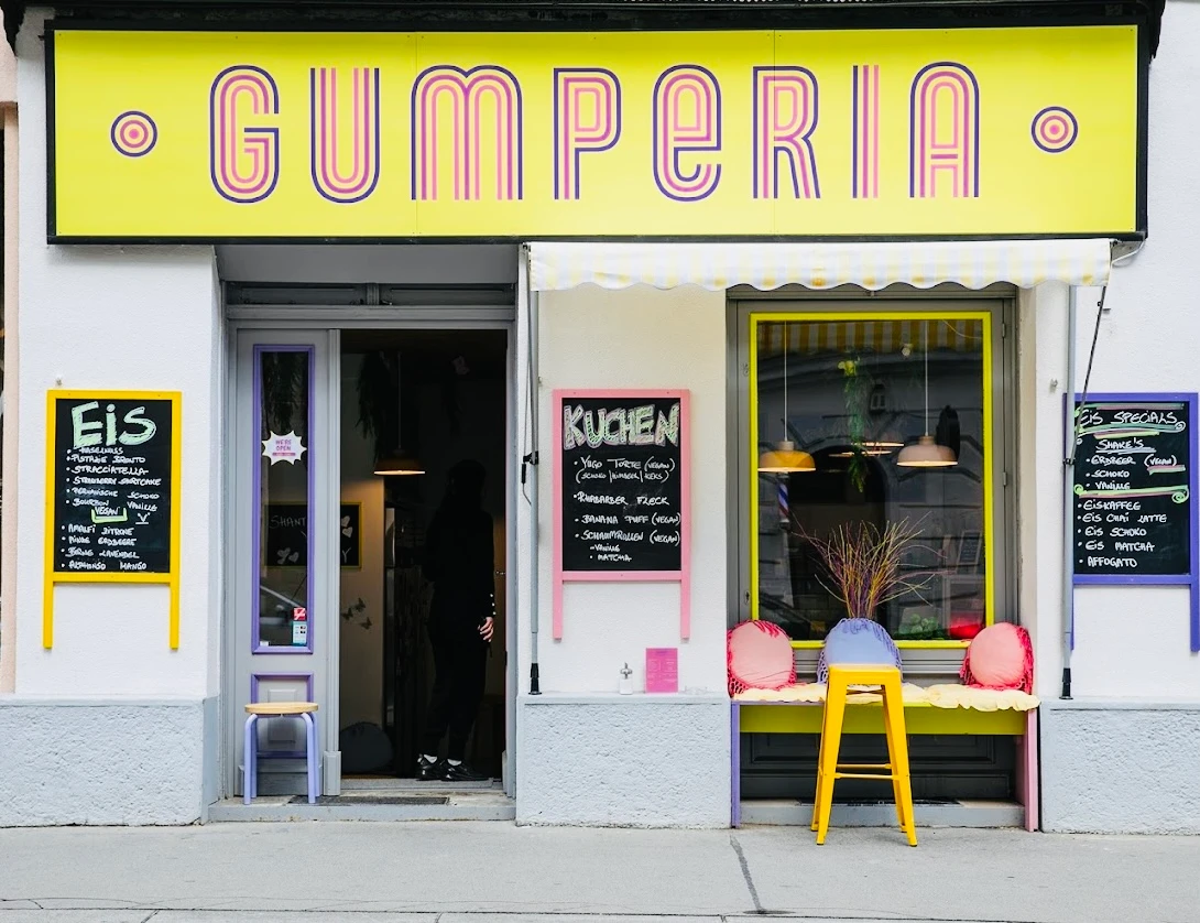 Fassade von GUMPERIA, einem Café mit farbenfrohen Eis- und Kuchenangeboten auf Tafeln.