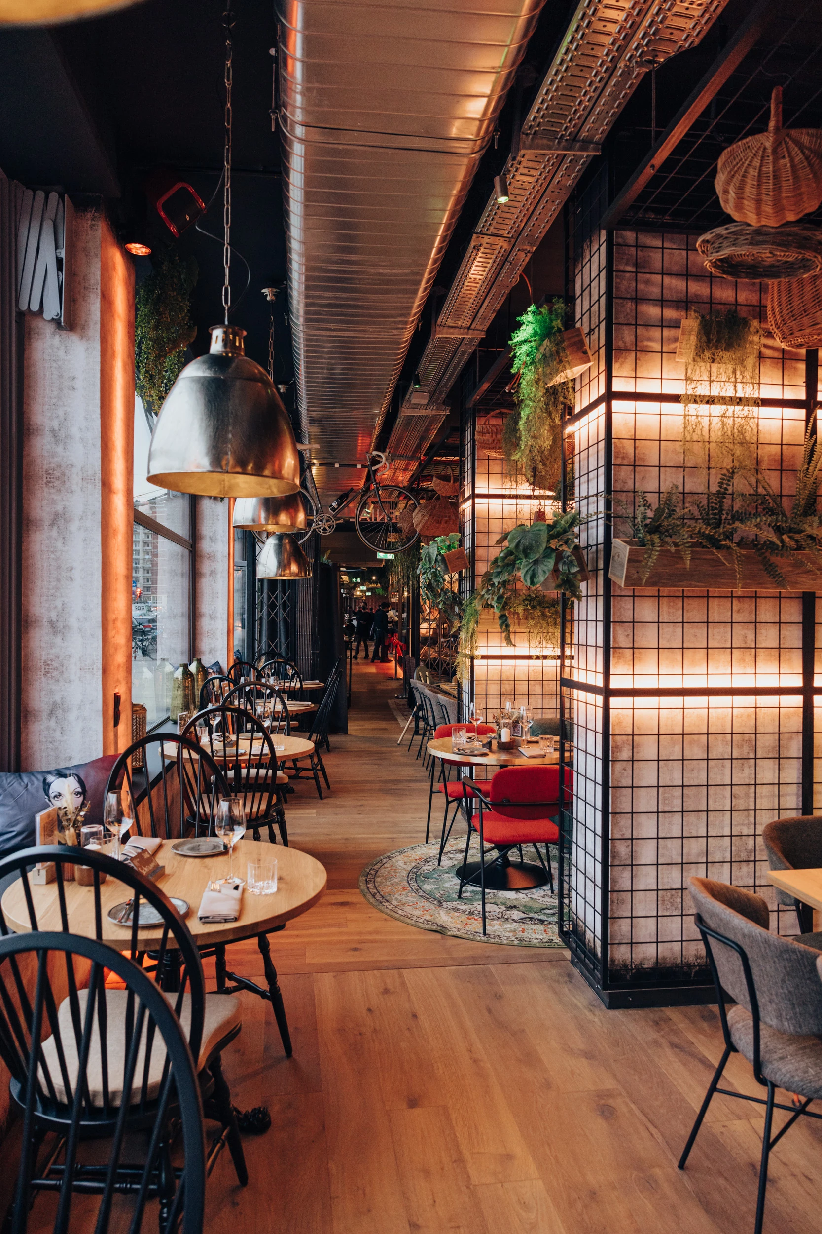 Stilvolles Restaurant mit Holzboden, runden Tischen und Industriedecke.