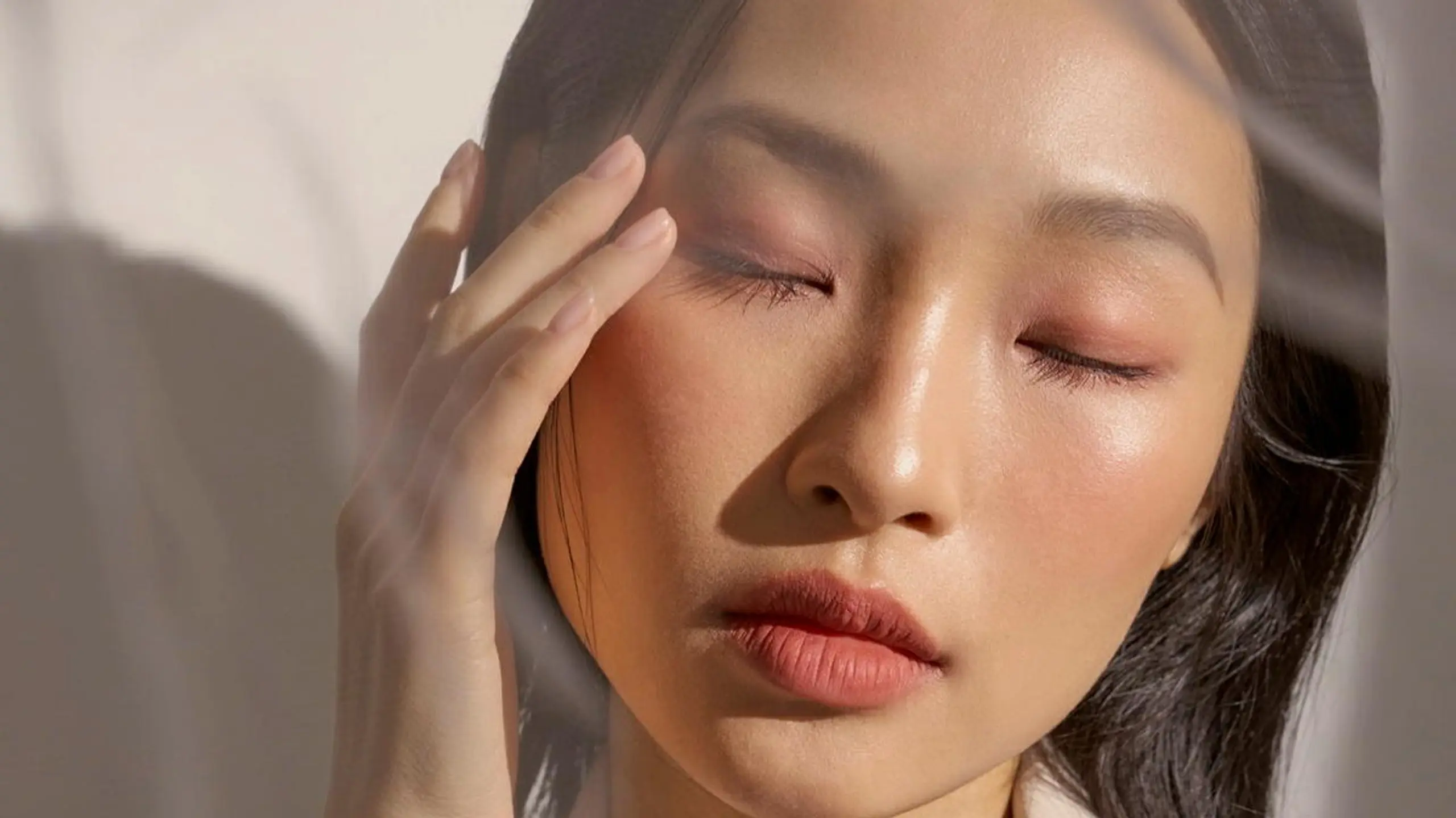 Frau mit geschlossenen Augen greift sich an die Schläfe