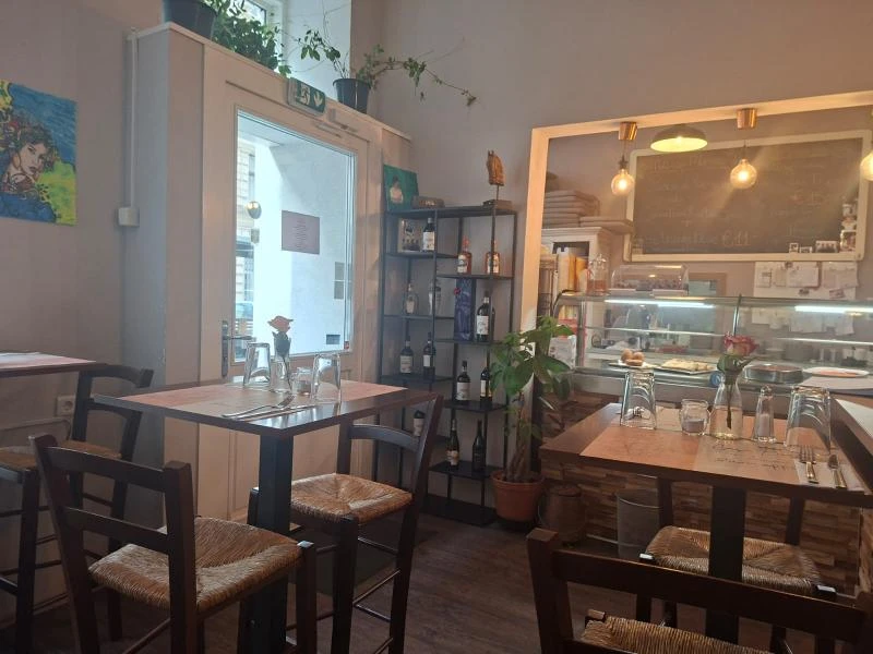 Einladendes Restaurant mit gedeckten Tischen, Weinregal und gemütlicher Atmosphäre.