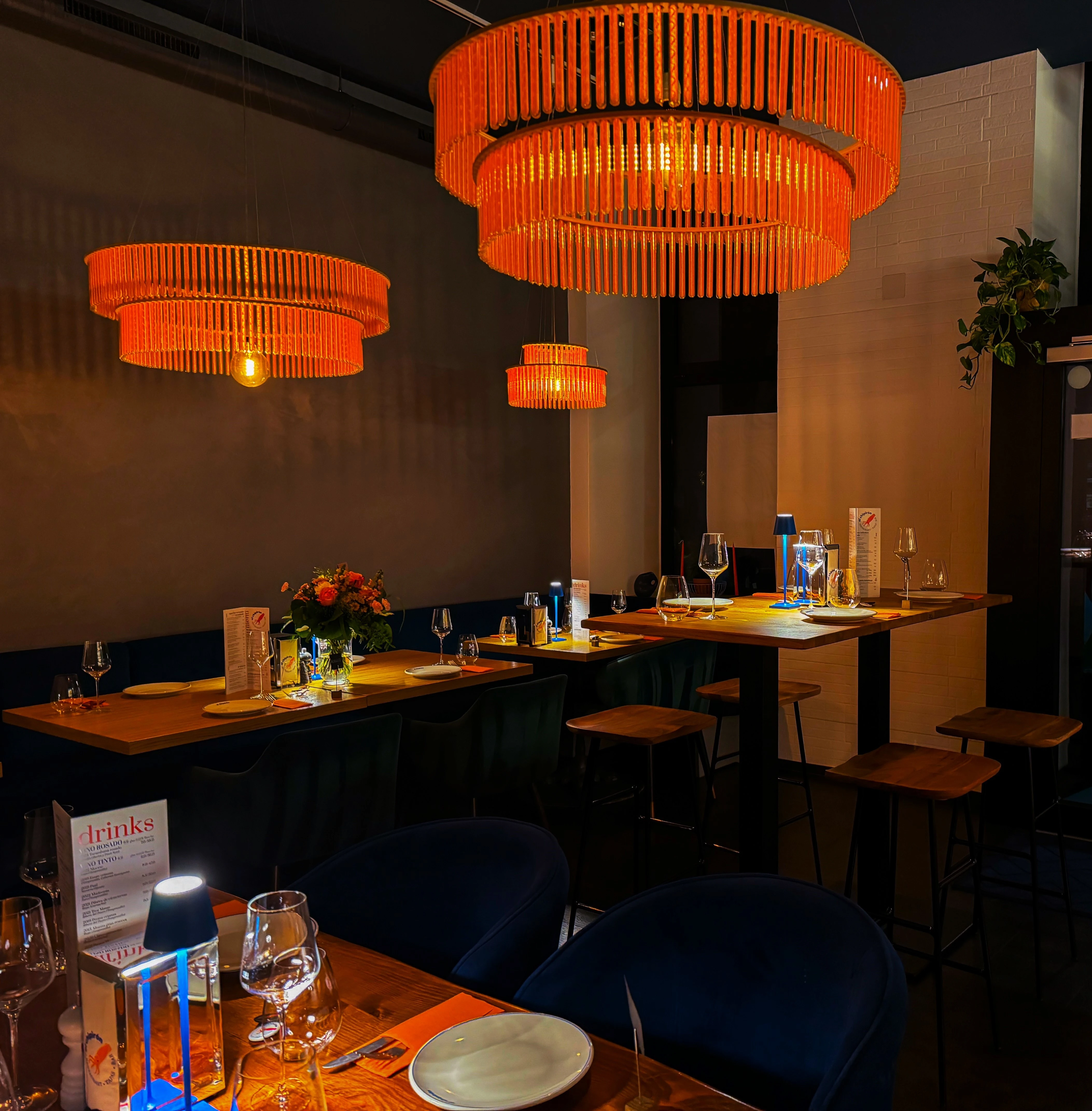 Elegantes Restaurant Interieur mit orangefarbenen Leuchten und gedeckten Holztischen