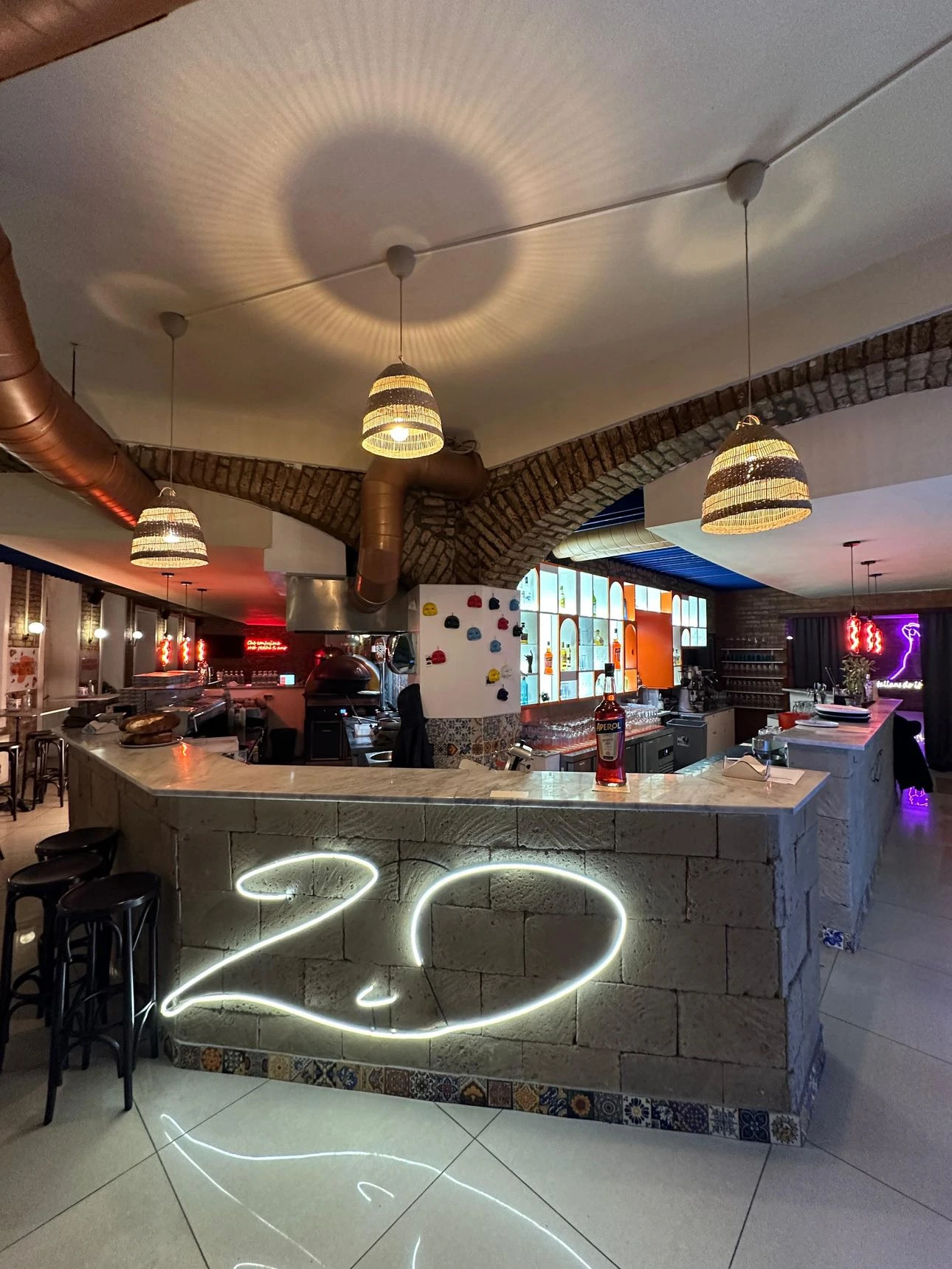 Innenaufnahme einer Bar/Restaurant-Szene mit Tresen, Beleuchtung und Dekoration.