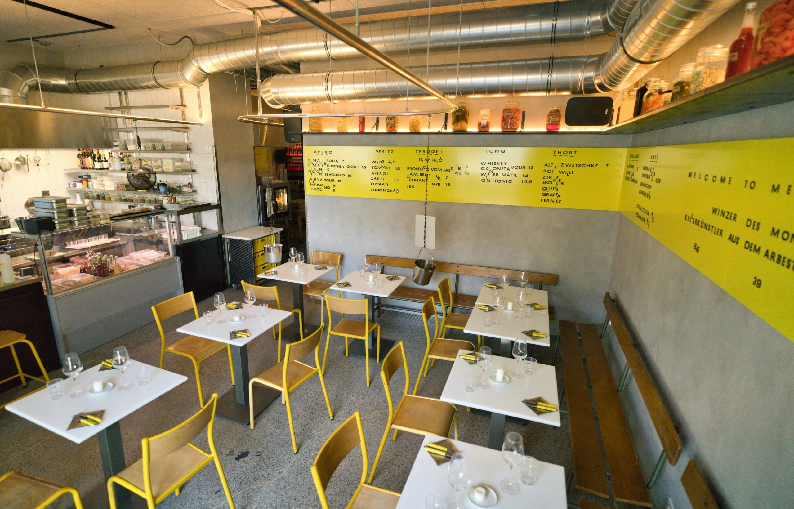 Restaurant-Innenraum mit gelben Stühlen und Menütafel an der Wand.