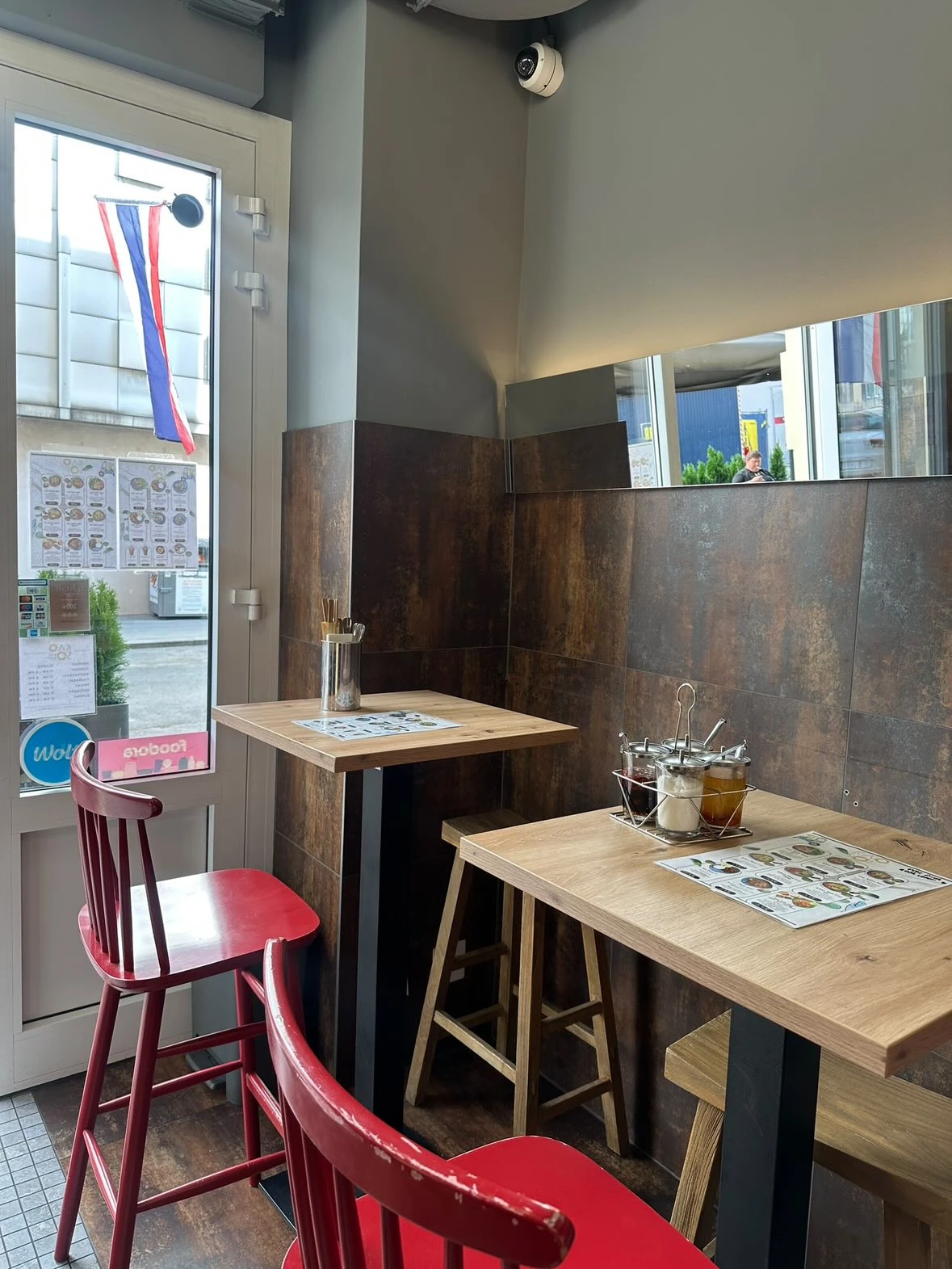 Innenraum eines kleinen thailändischen Restaurants mit Tischen, Stühlen und thailändischer Flagge.