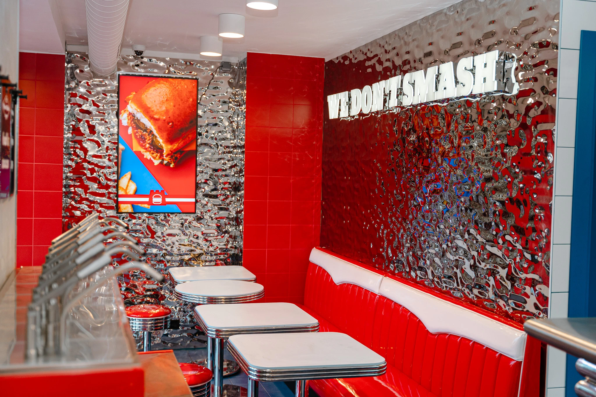 Innenaufnahme eines stilvollen Diner-Restaurants im Retro-Stil mit roten Sitzen und einer glänzenden Wand.