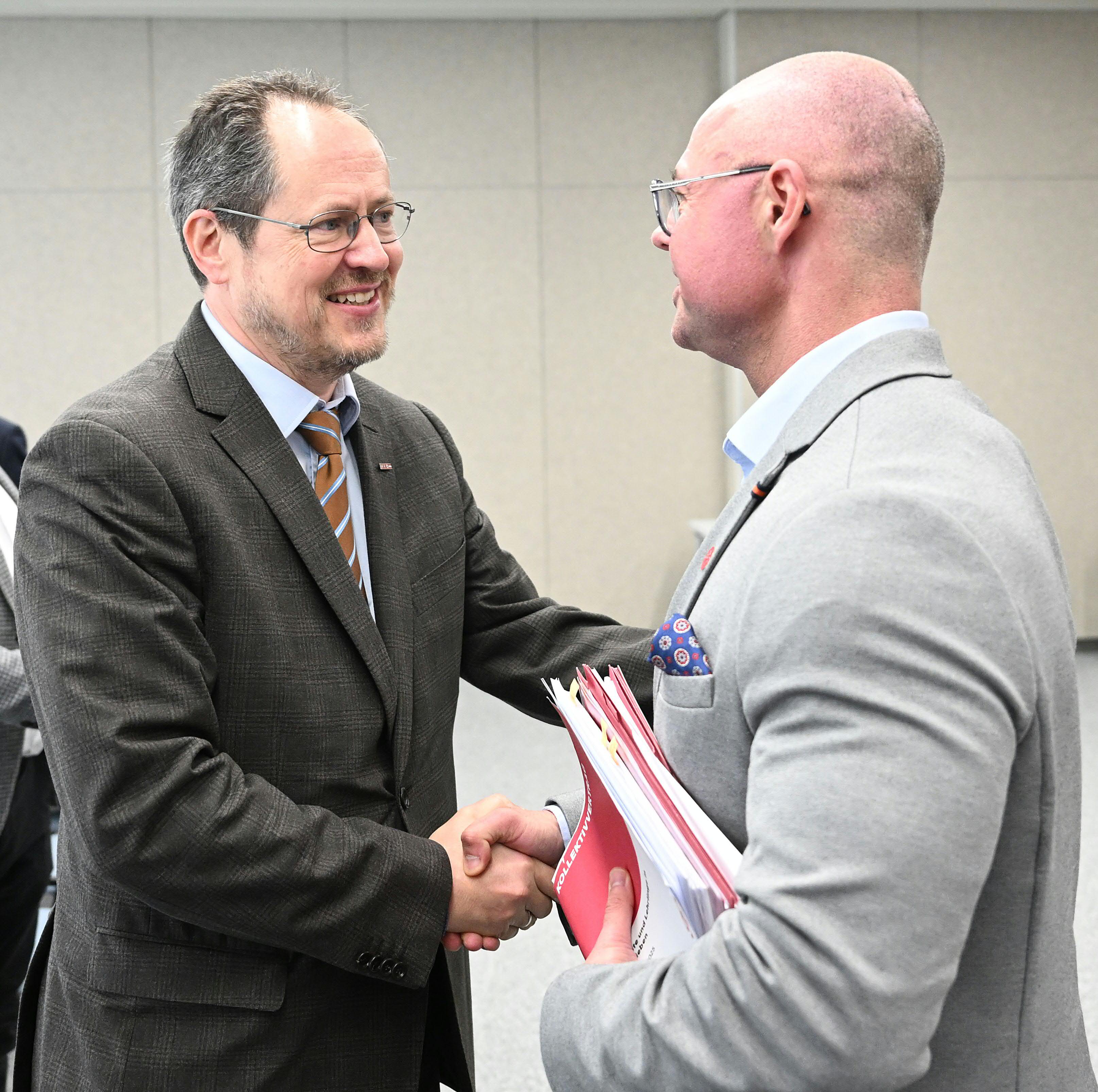 WKÖ-Handelsobmann Rainer Trefelik und GPA-Bundesgeschäftsführer und gewerkschaftlicher Chefverhandler Mario Ferrari lachen und geben sich die Hand