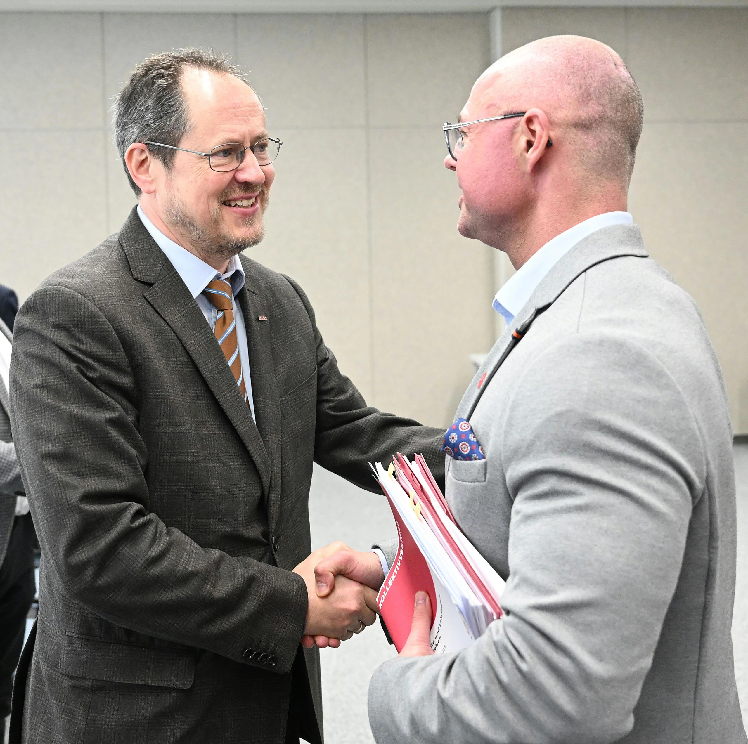 WKÖ-Handelsobmann Rainer Trefelik und GPA-Bundesgeschäftsführer und gewerkschaftlicher Chefverhandler Mario Ferrari lachen und geben sich die Hand