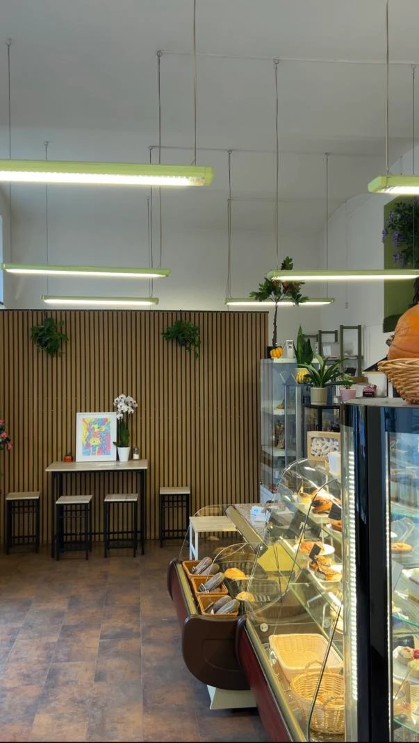 Café- oder Bäckerei-Interieur mit Backwaren, Holzverkleidung und moderner Beleuchtung.