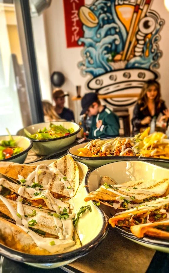 Nahaufnahme von Quesadillas, Nachos und Salat in einem Restaurant mit mexikanischer Küche.