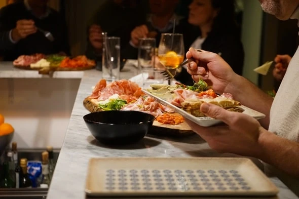 Gruppe genießt Appetithäppchen mit Prosciutto und Käse in Restaurant/Bar. Gesellige Runde mit Essen und Getränken.