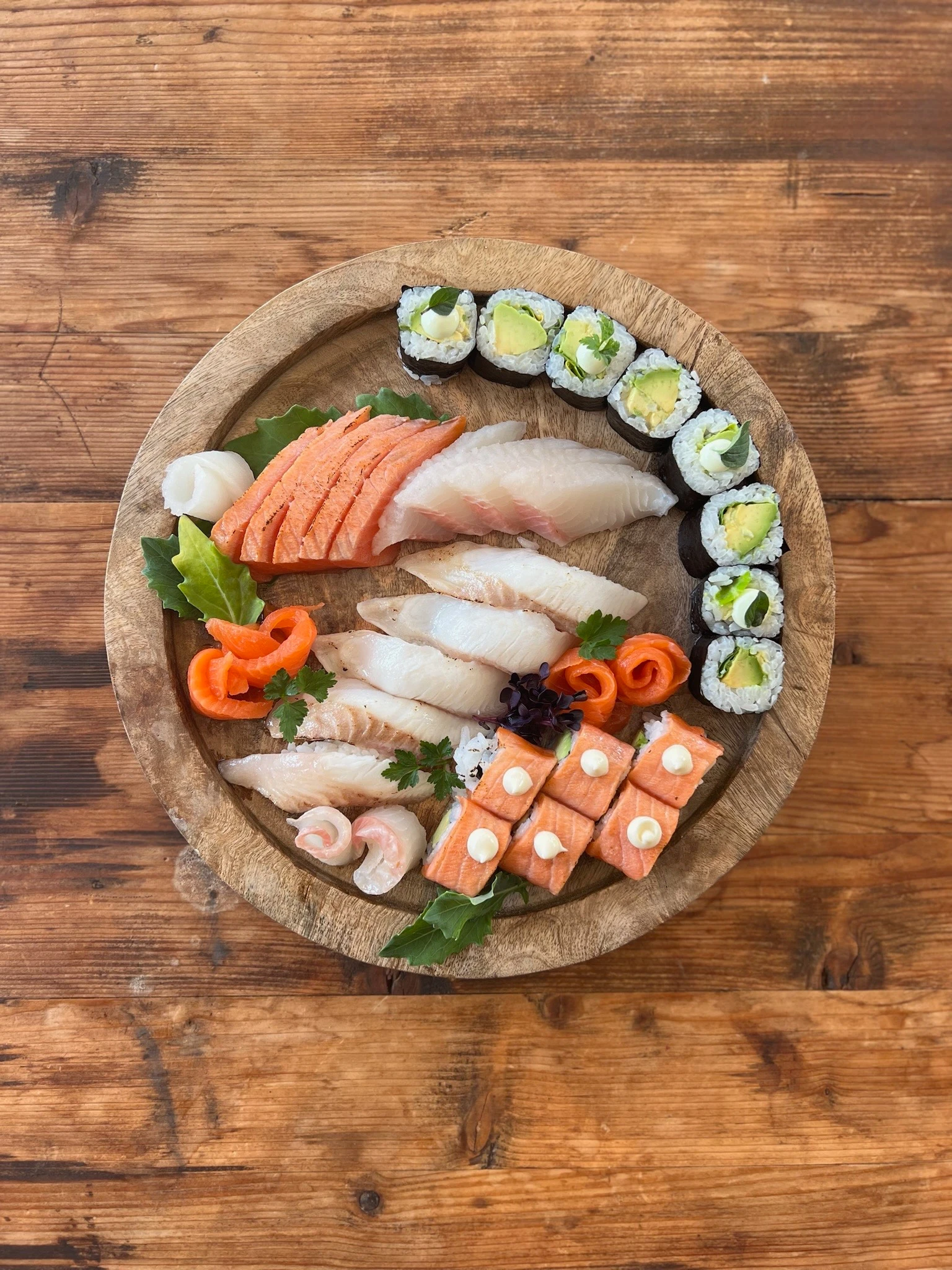 Sushi Platte mit Maki, Nigiri und Sashimi auf einem Holzteller.