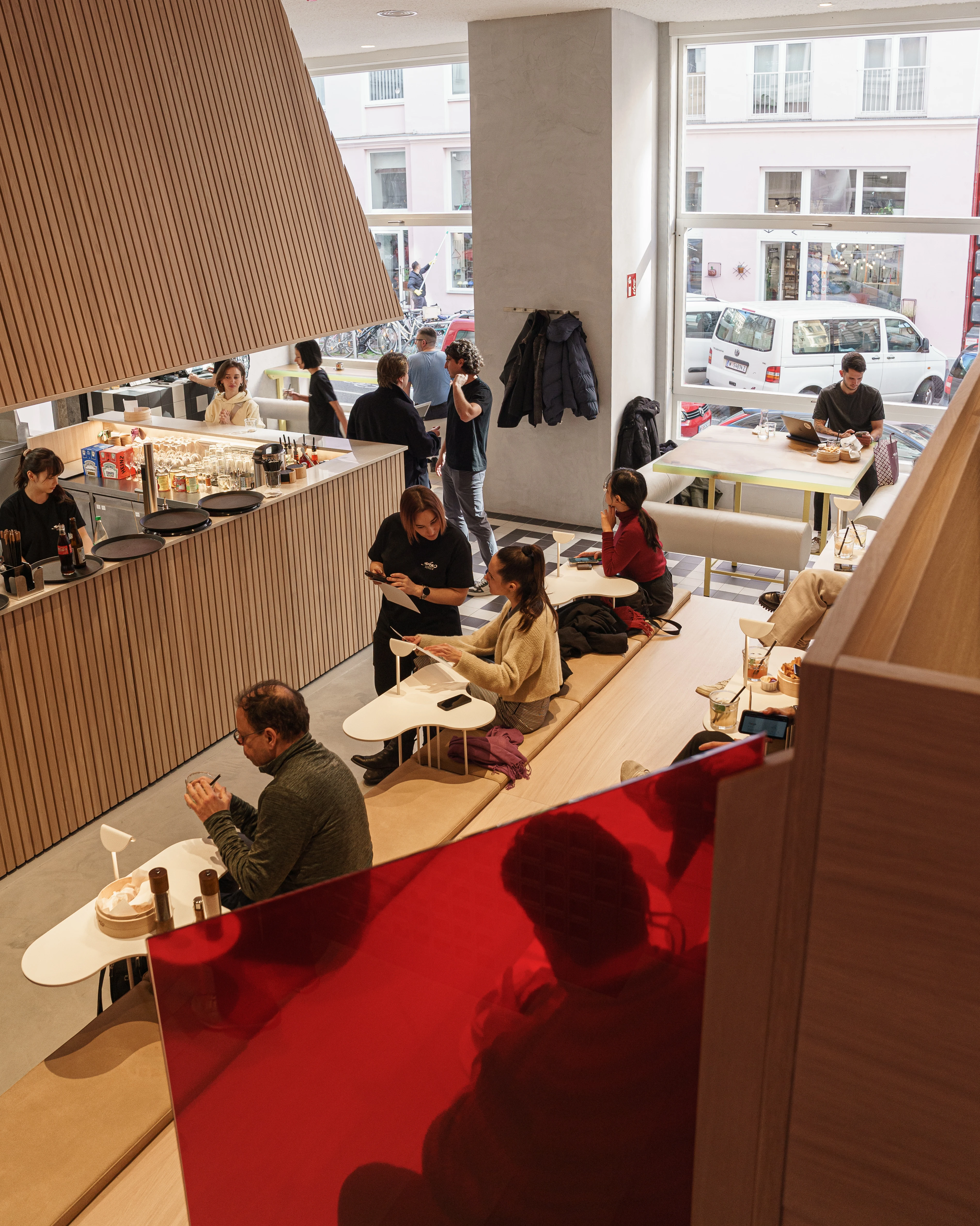 Modernes Café-Interieur mit Gästen, Holzvertäfelung und Tageslicht.