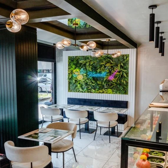 Interieur eines modernen Restaurants mit grüner Wand und Tischen.
