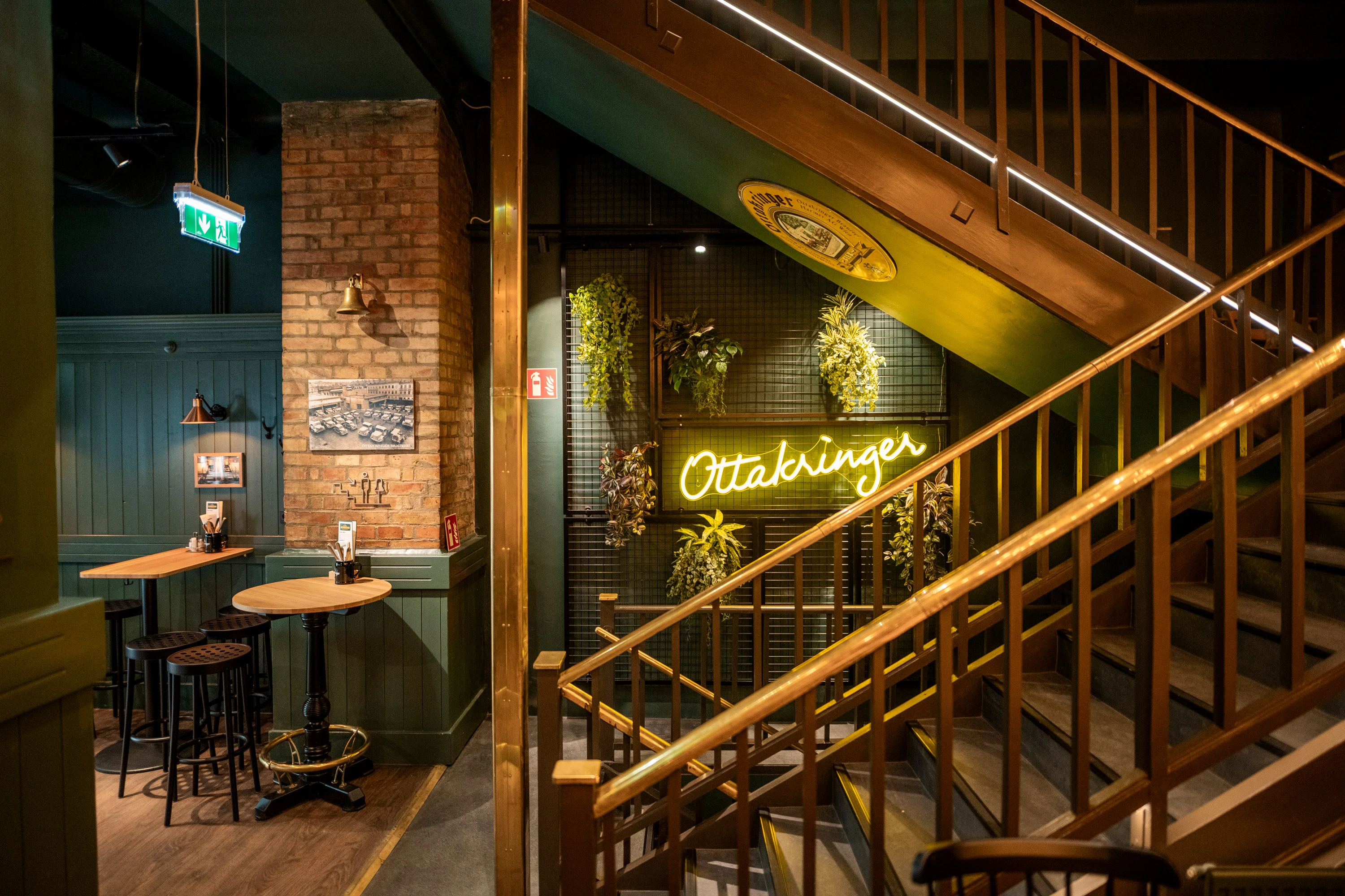 Stilvolles Restaurant Interieur mit Treppe und Ottakringer Leuchtreklame.