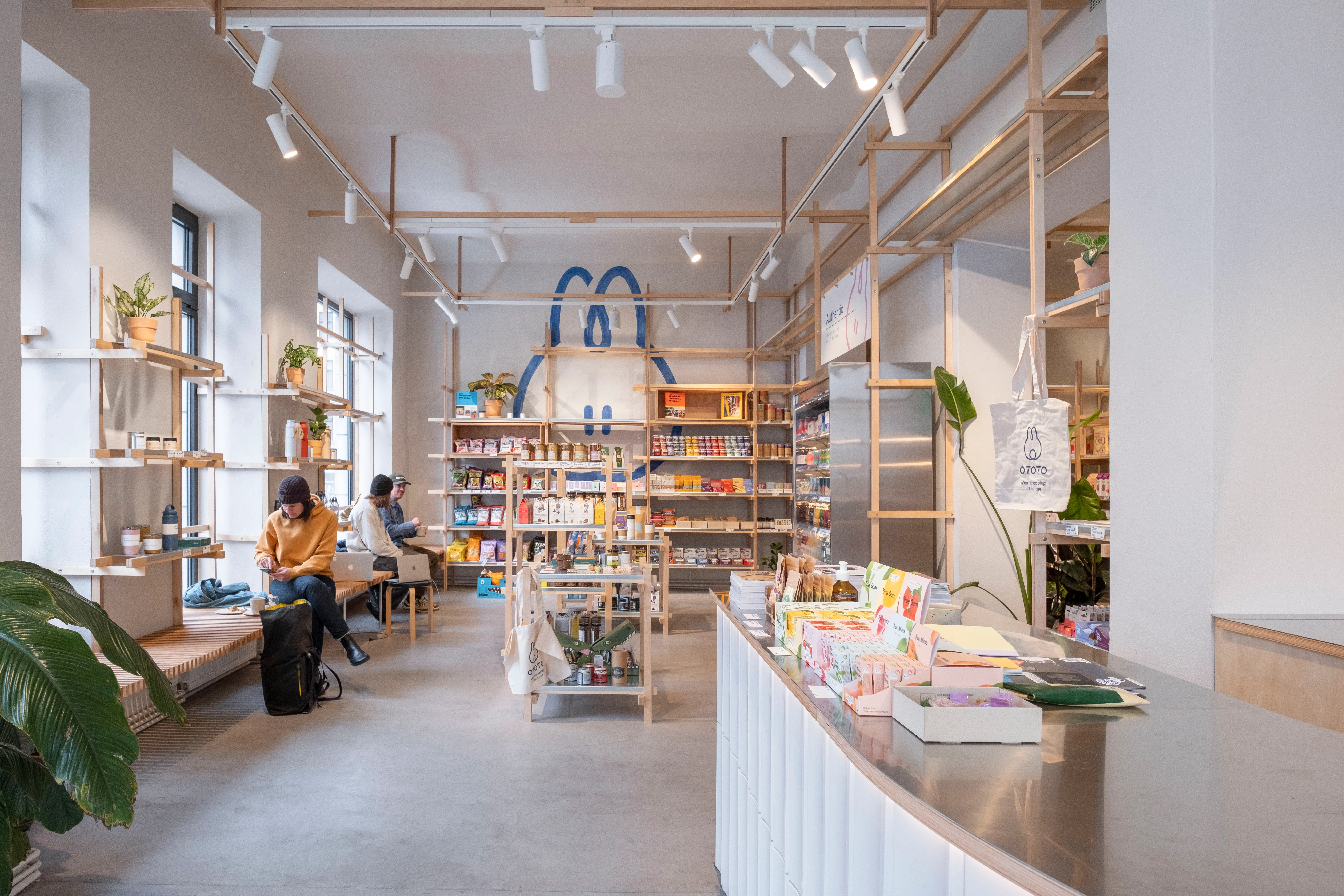 Innenansicht eines modernen Geschäfts mit Personen, Regalen und minimalistischem Design.