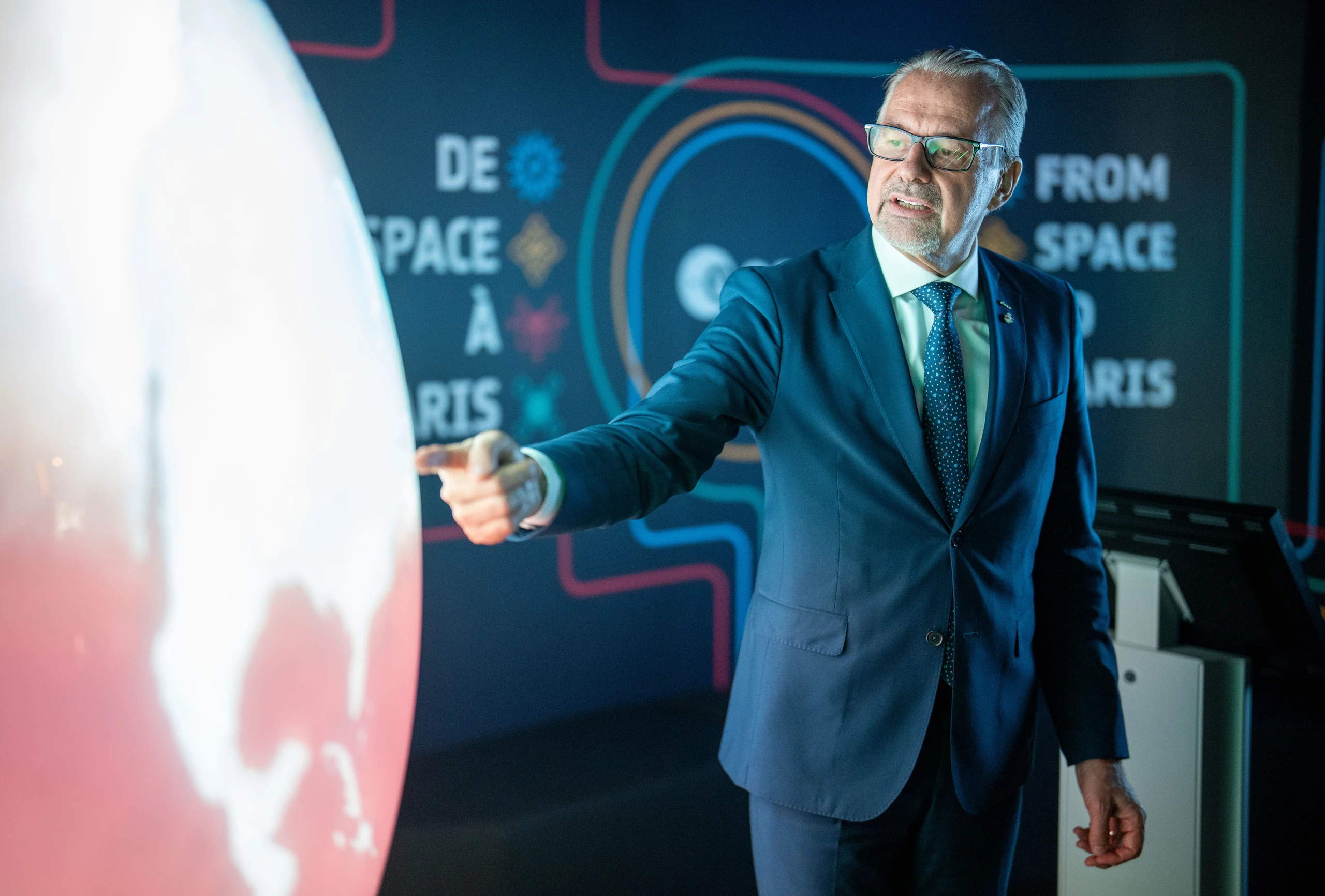 Mann, der auf einen großen Globus zeigt, vor schwarzem Hintergrund