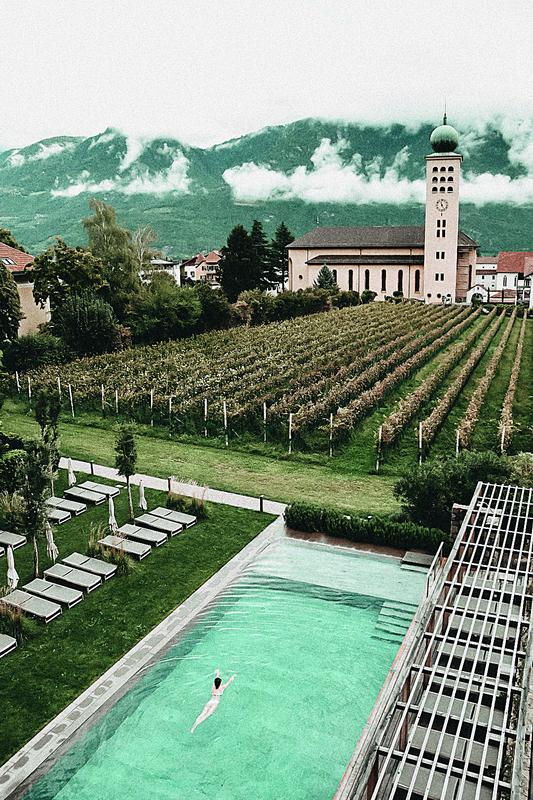 Swimmingpool umgeben von Äpfelbäumen, einer Kirchhe und Bergen