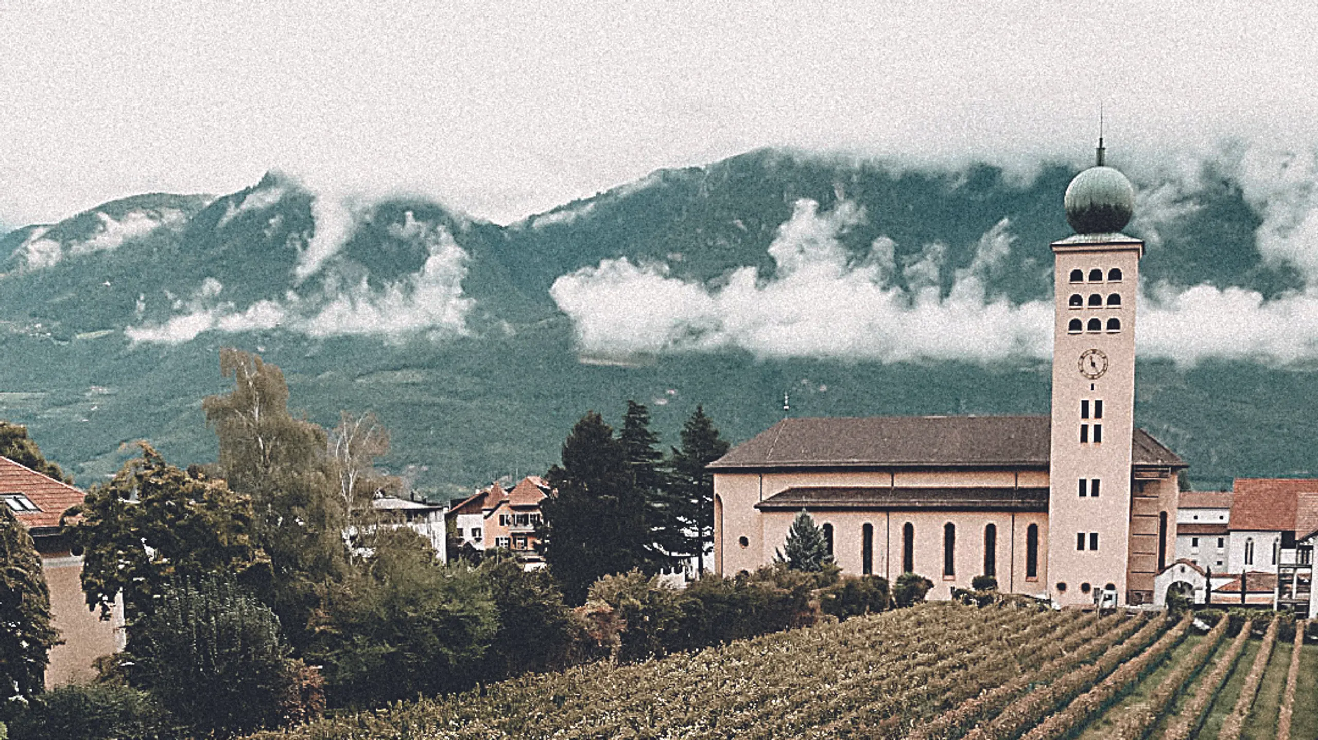 © Hotel Schwarzschmied Swimmingpool umgeben von Äpfelbäumen, einer Kirchhe und Bergen