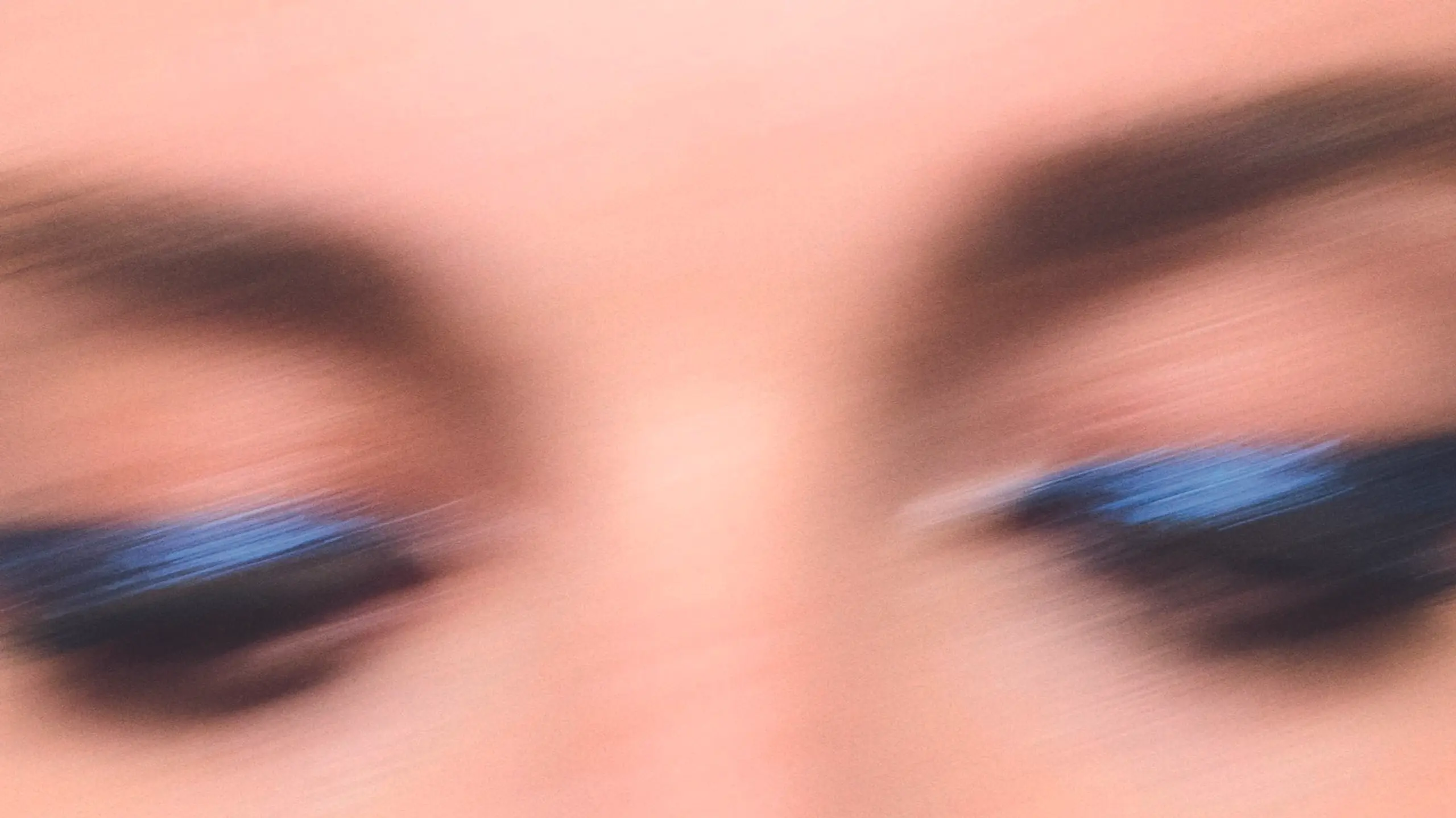 Close-up von verschwommenem Gesicht mit glitzerndem blauen Lidschatten