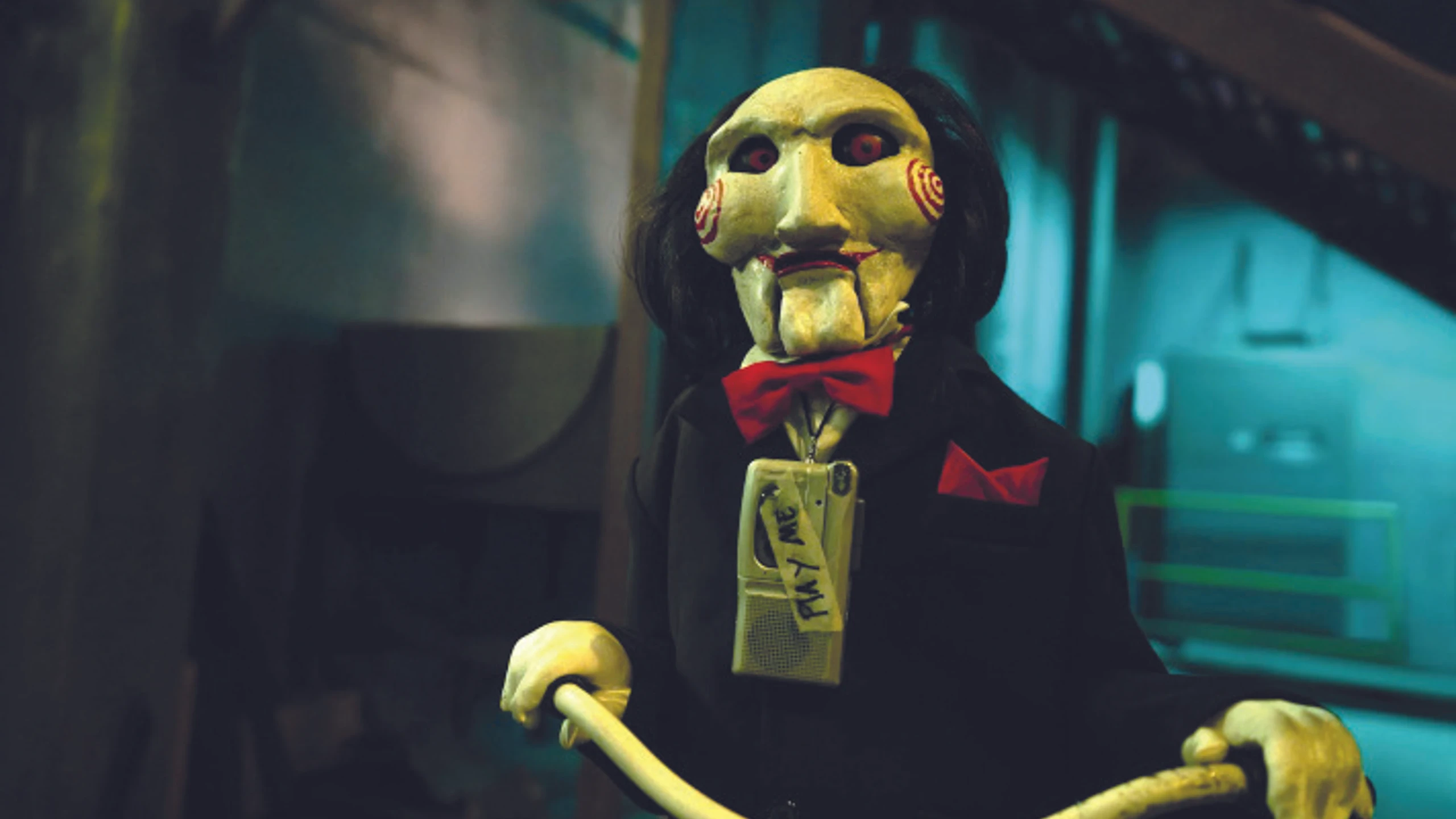 Jigsaw Puppe sitzt auf einem Rad mit Kassettenspieler um den Hals