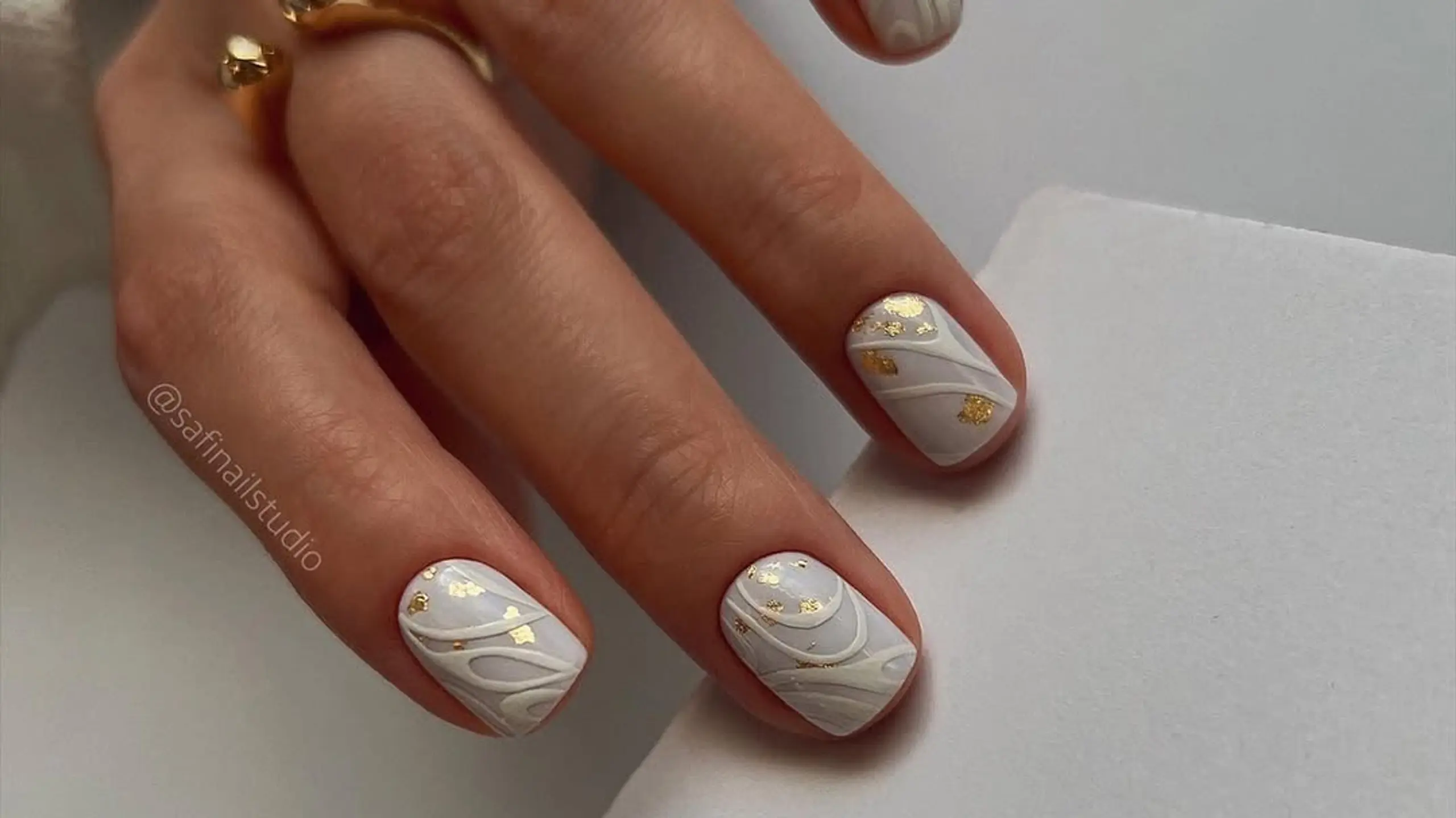 Bild von Maniküre: weiße Nägel mit weißen Liniendesigns und Gold-Plättchen-Details