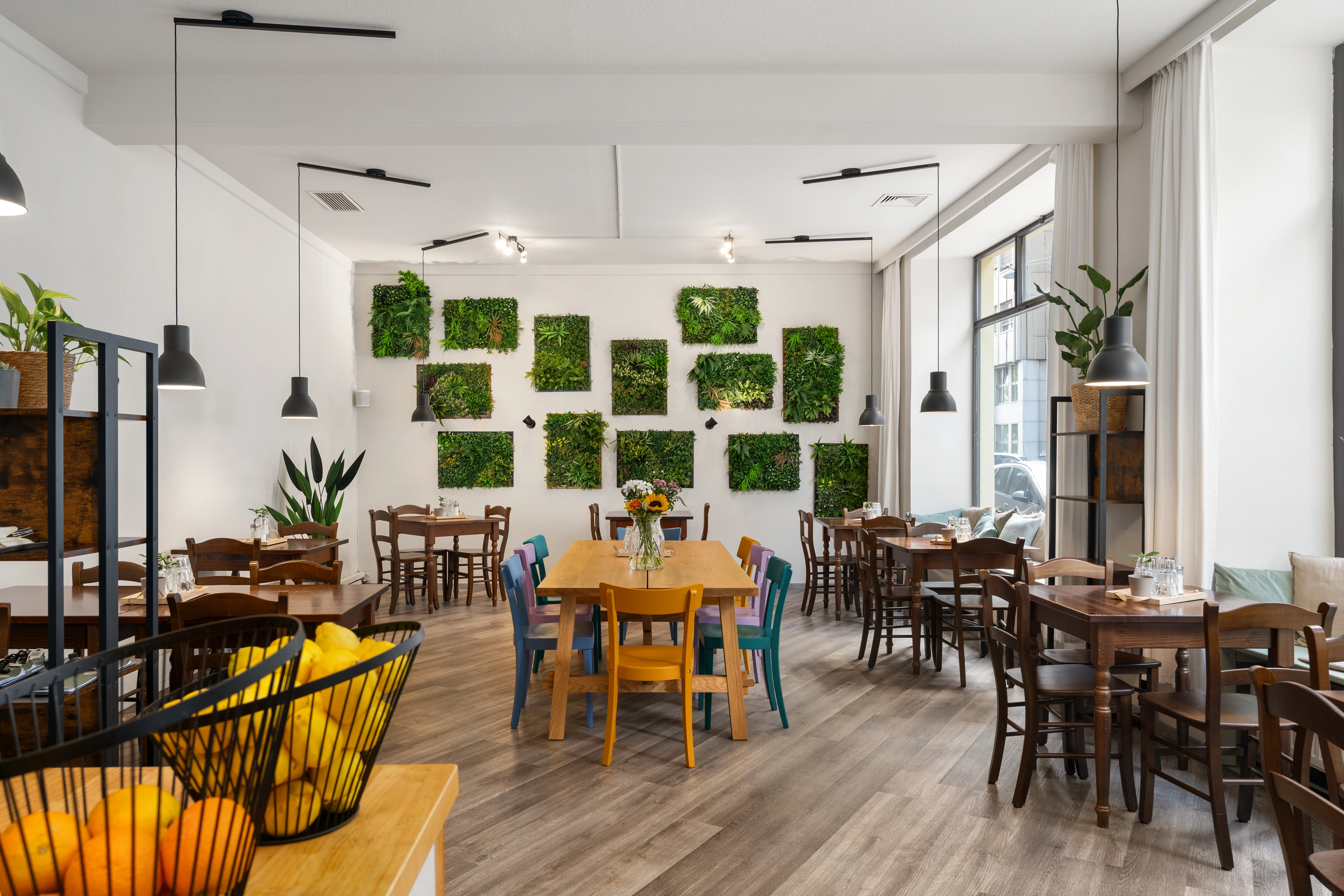 Helles Restaurant mit grüner Wanddeko, Tischen und Stühlen. Einladende Atmosphäre.