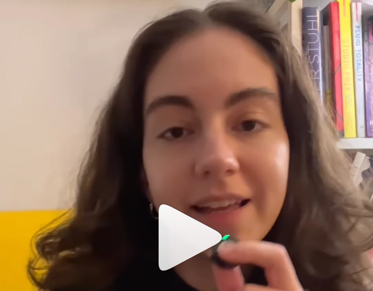 Junge Frau vor Bücherregal, wahrscheinlich Influencerin/Vloggerin. Videoaufnahme oder Livestream.