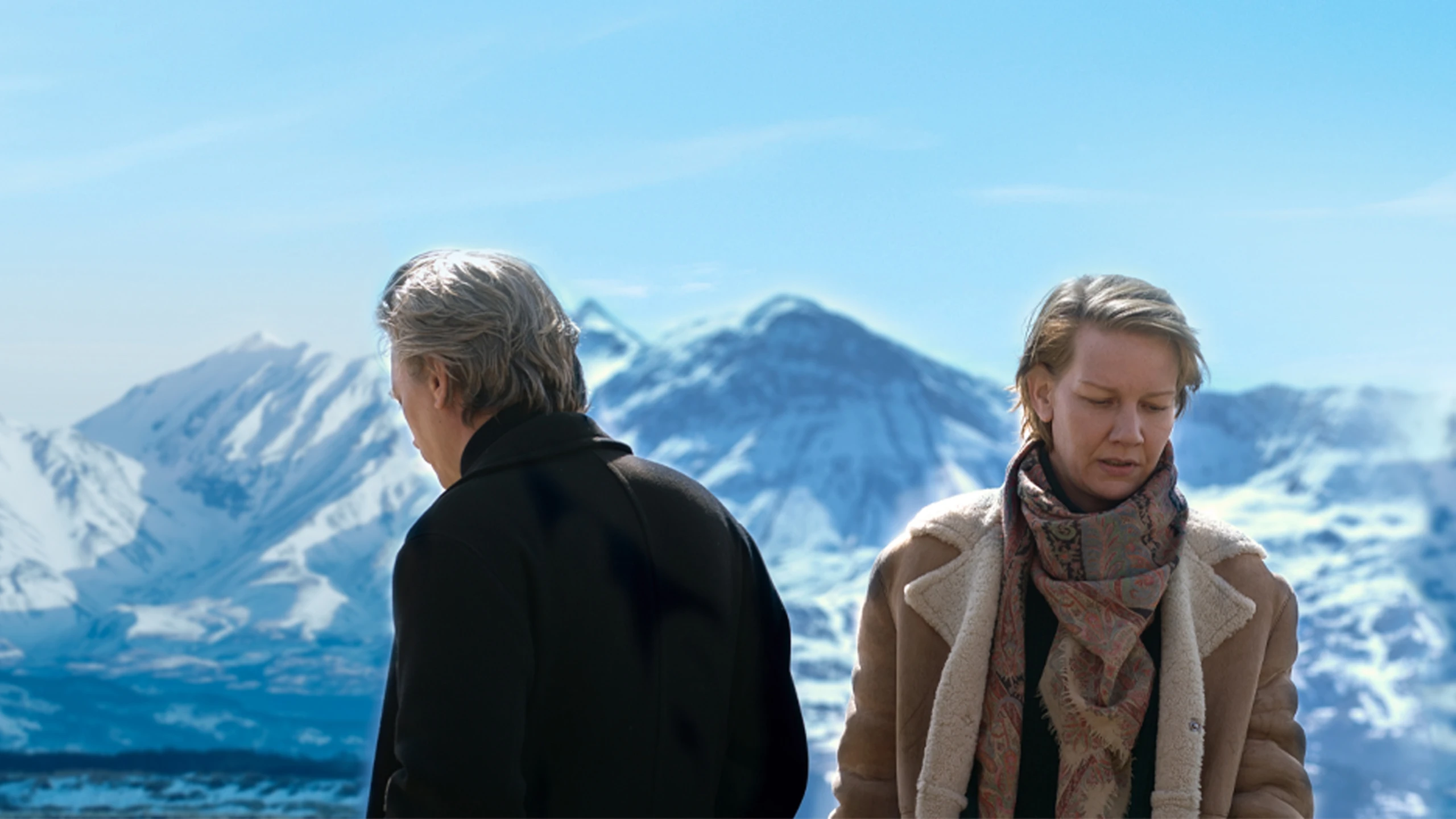 Sandra Hüller und ein Mann, dessen Gesicht abgewandt ist, stehen vor einer schneebedeckten Bergkette