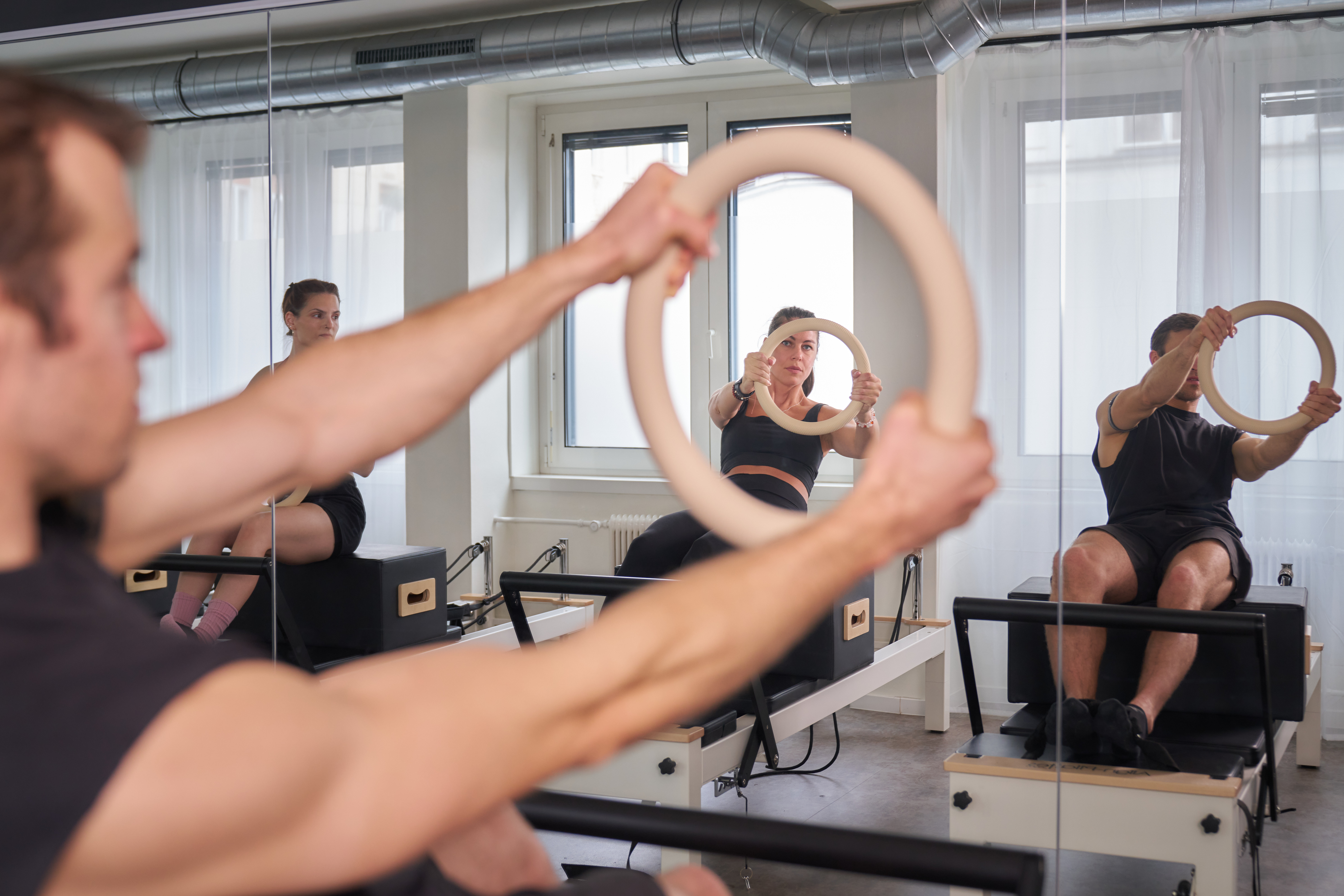 Frauen und ein Mann die Reformer Pilates machen