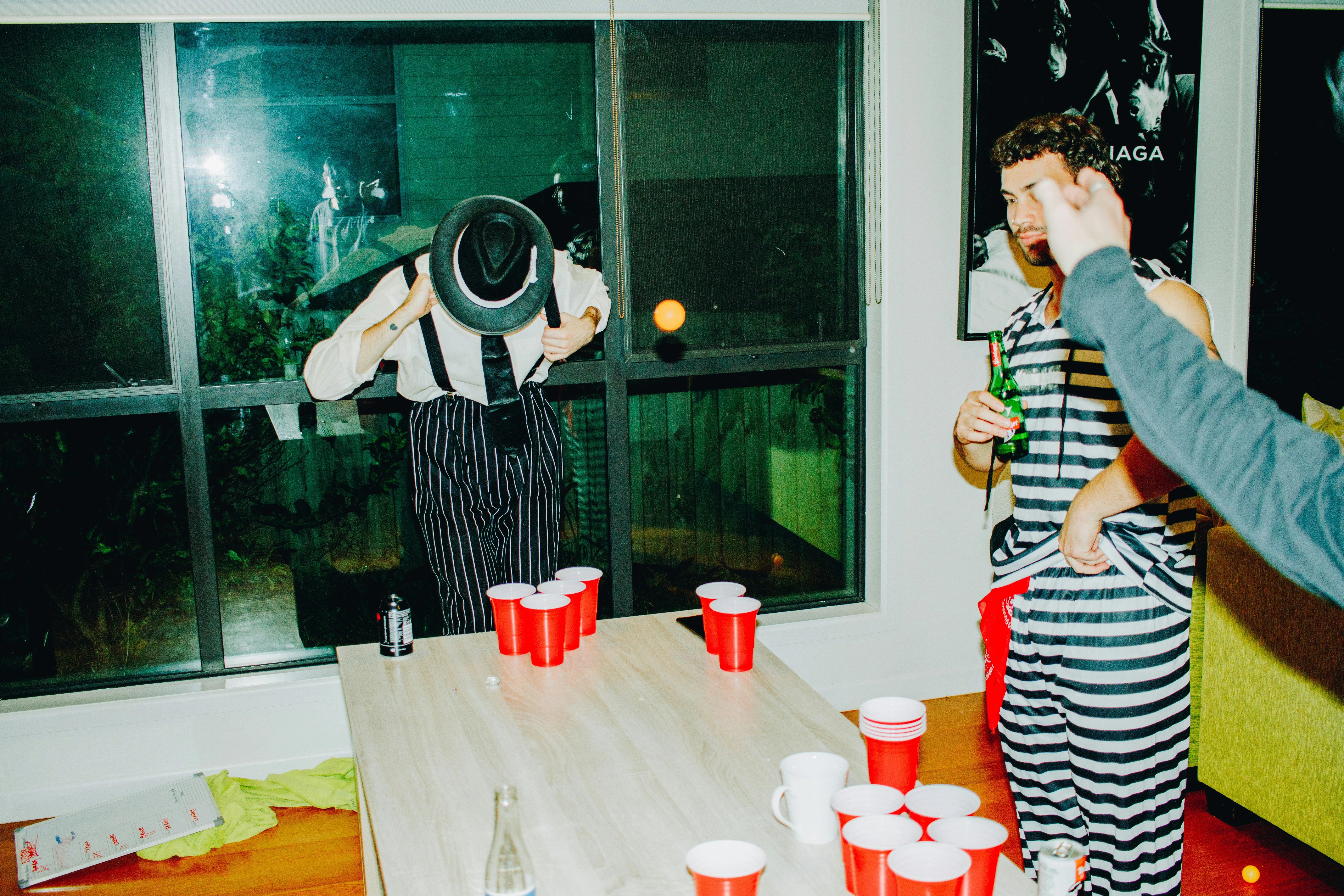 Party-Szene mit Menschen in Kostümen, Tisch mit roten Bechern für Beer Pong, ungezwungene und unterhaltsame Atmosphäre