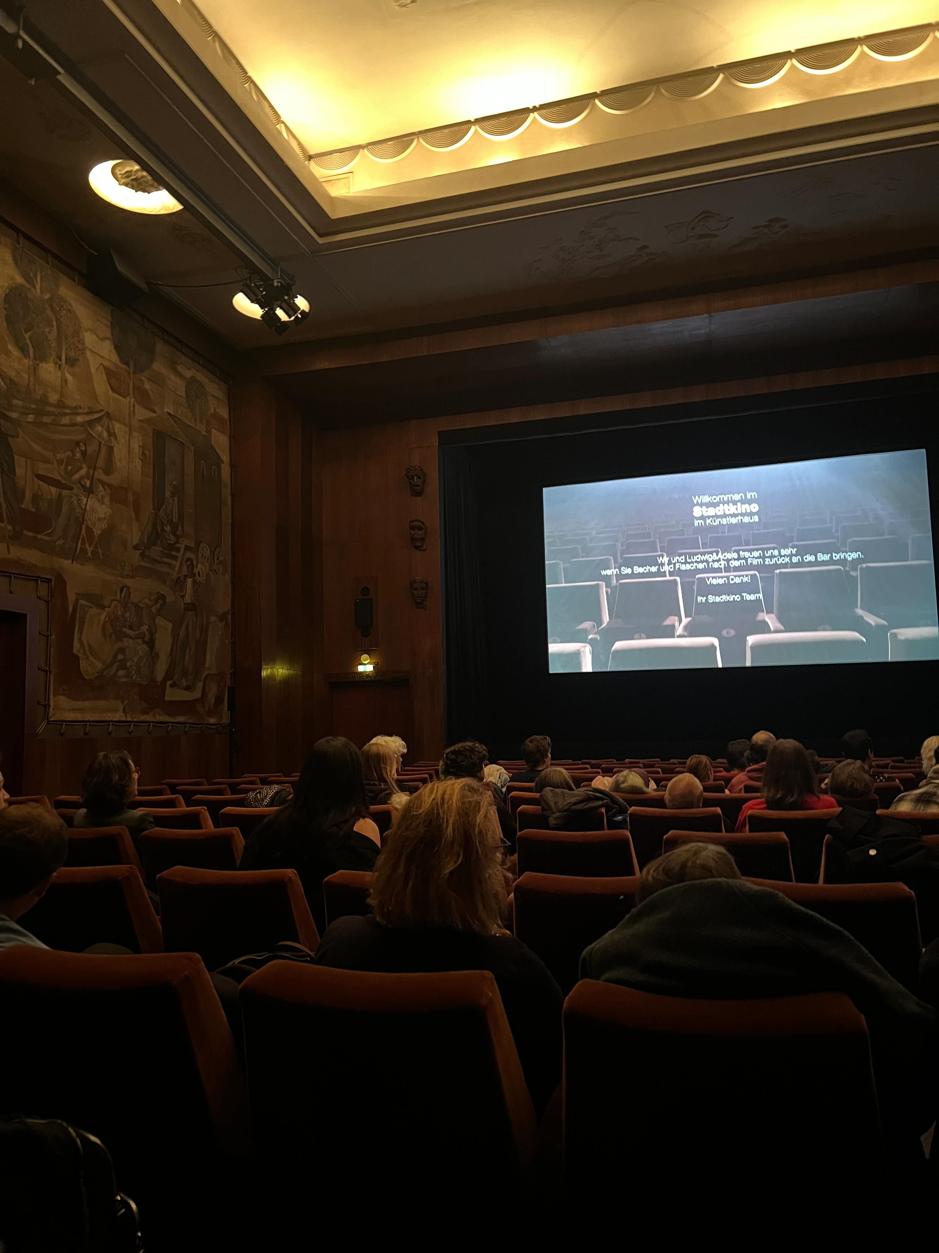 Innenansicht Kinosaal Stadtkino Wien mit Leinwand, Publikum und roter Bestuhlung.