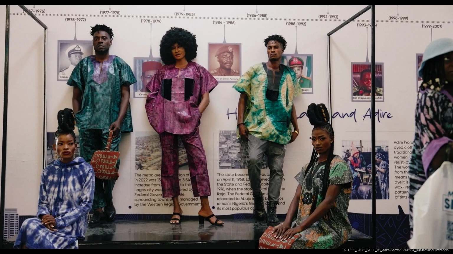 Personen in traditioneller nigerianischer Adire-Kleidung vor Ausstellung