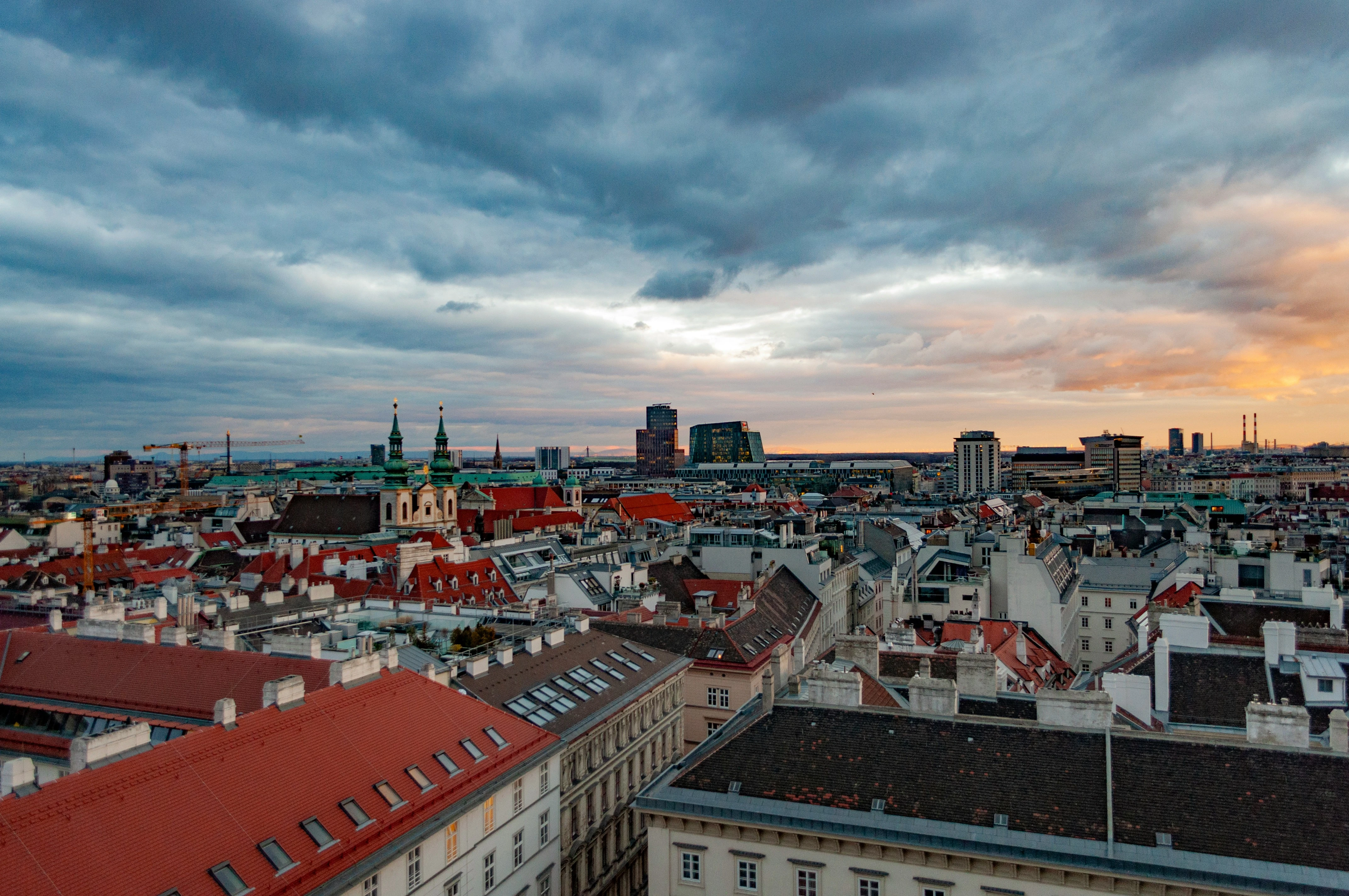 Panoramaaufnahme von Wien, Österreich, mit Blick auf rote Ziegeldächer und beeindruckenden Wolken.
