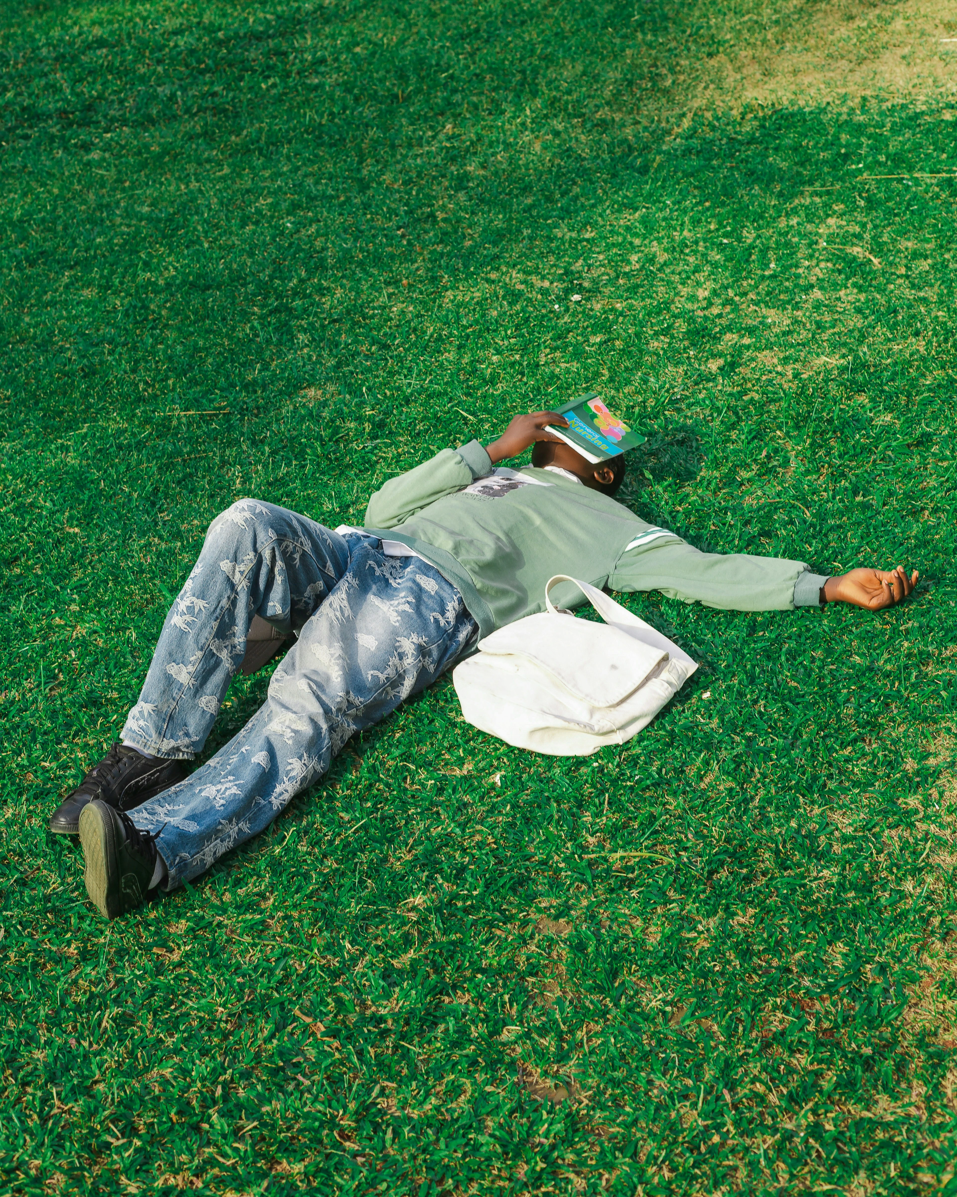 Man sleeping on grass with a book on his face