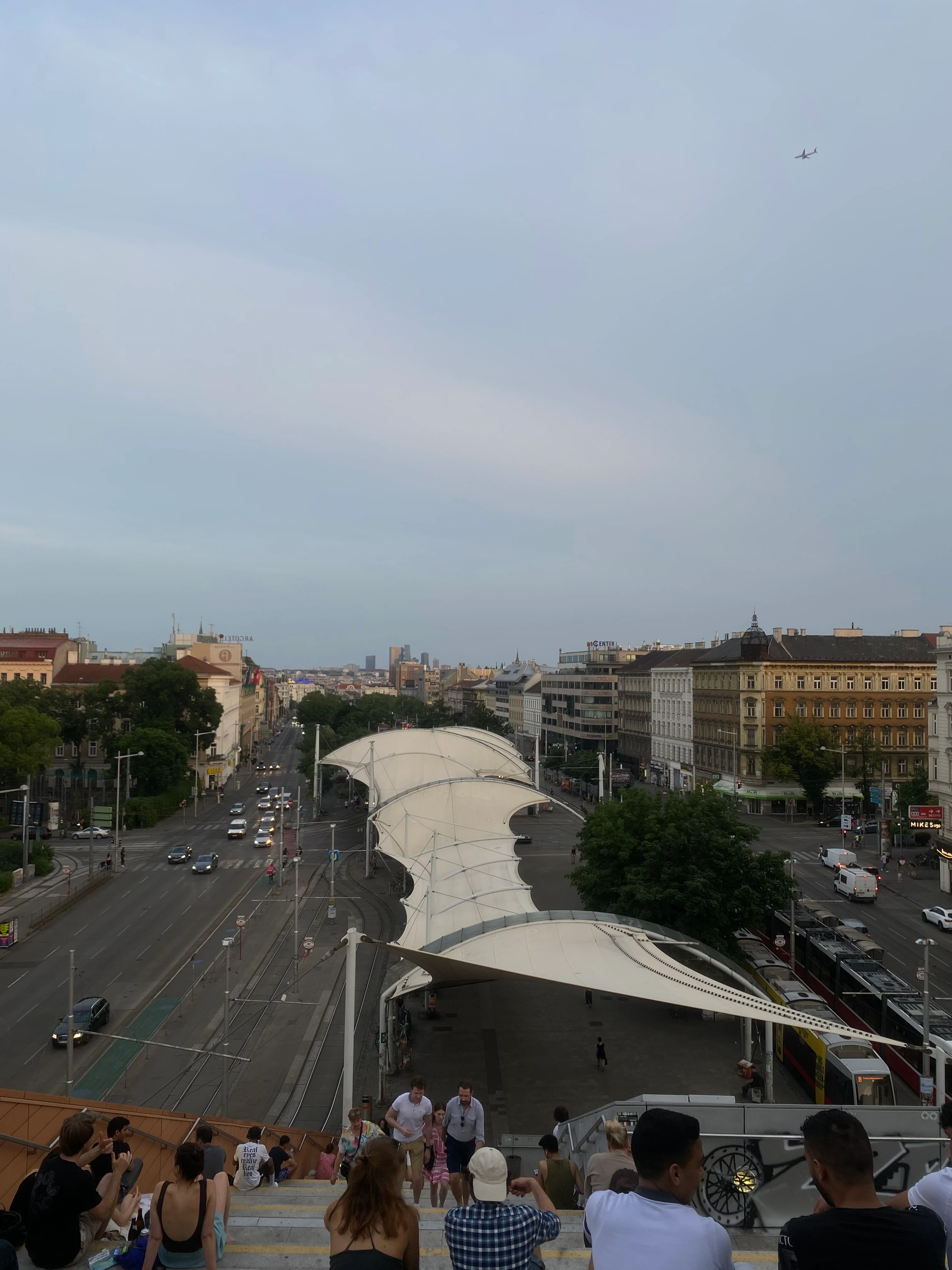 Luftaufnahme einer belebten Stadtstraße mit Flugzeug im Himmel