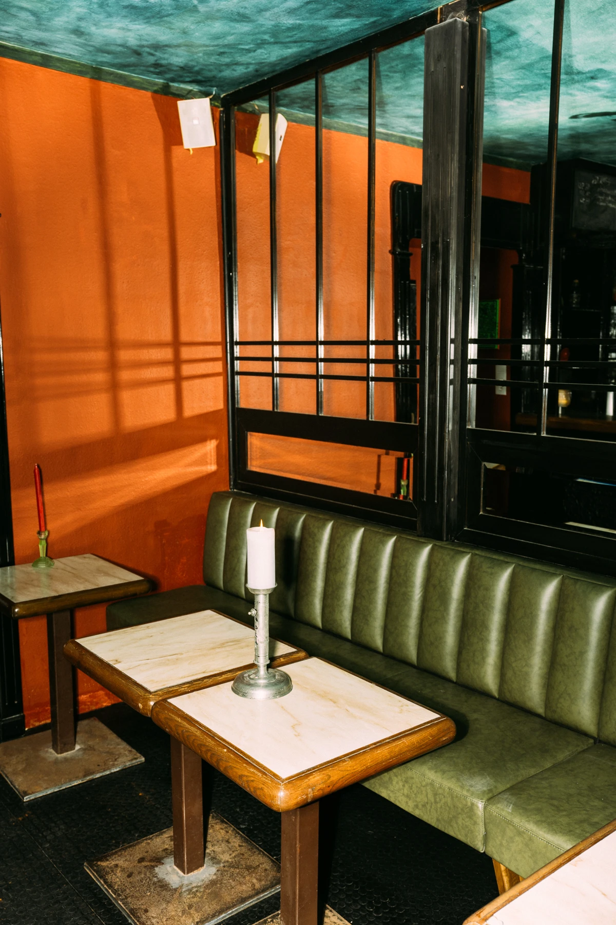 Innenaufnahme einer Bar mit Tischen, Sofa und Kerze