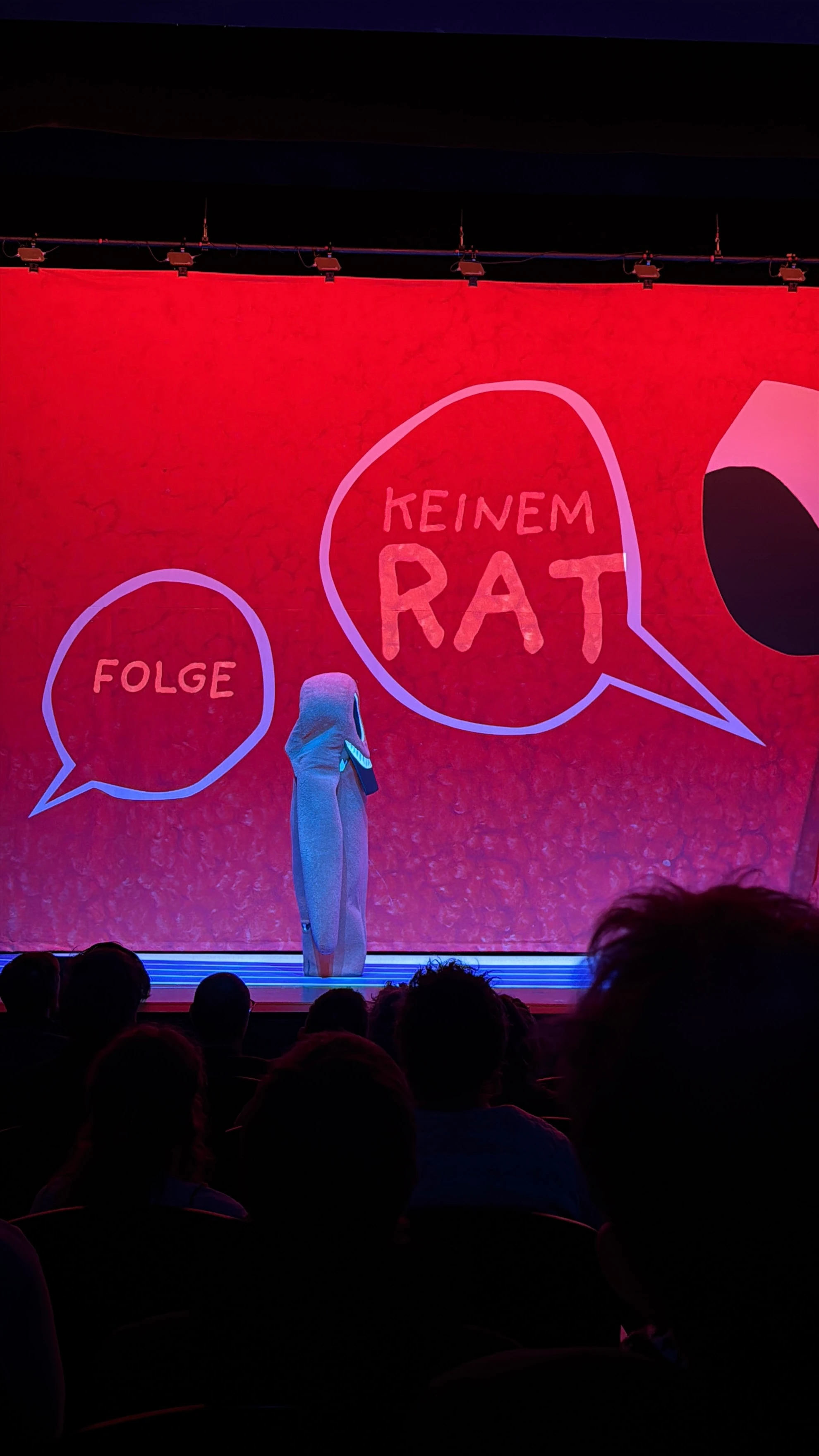 Aufführung im Volkstheater Wien mit rotem Bühnenbild und Publikum