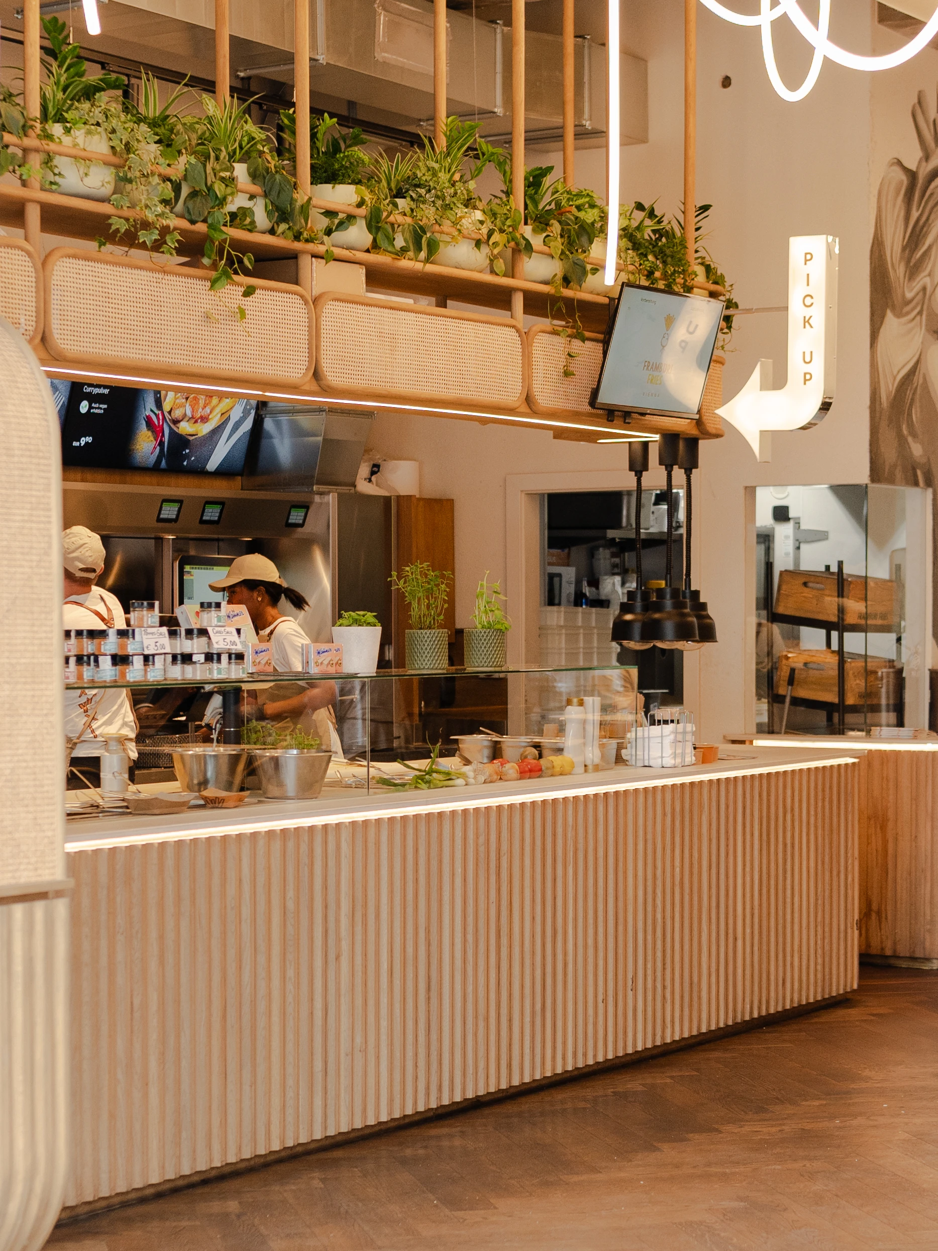 Innenaufnahme eines Restaurants mit Theke, Pflanzen und Mitarbeitern